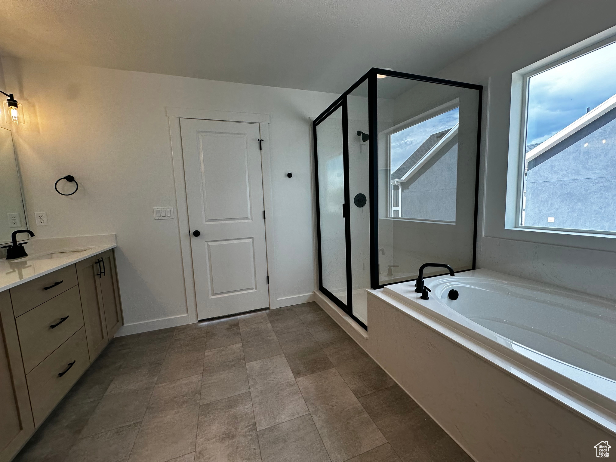 Bathroom featuring separate shower and tub, tile flooring, and vanity