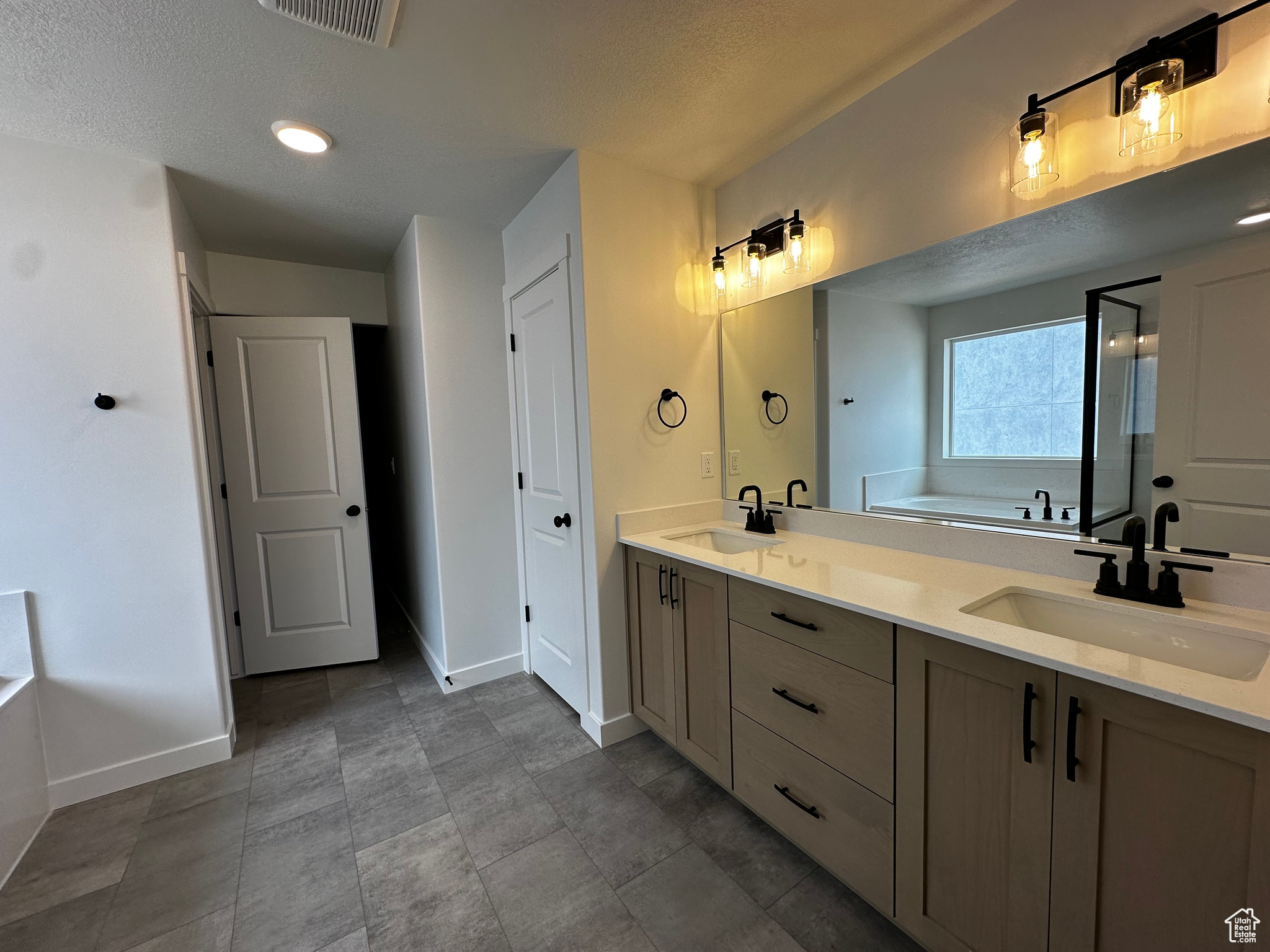 Bathroom featuring tile flooring, double vanity, a bath to relax in, and a textured ceiling