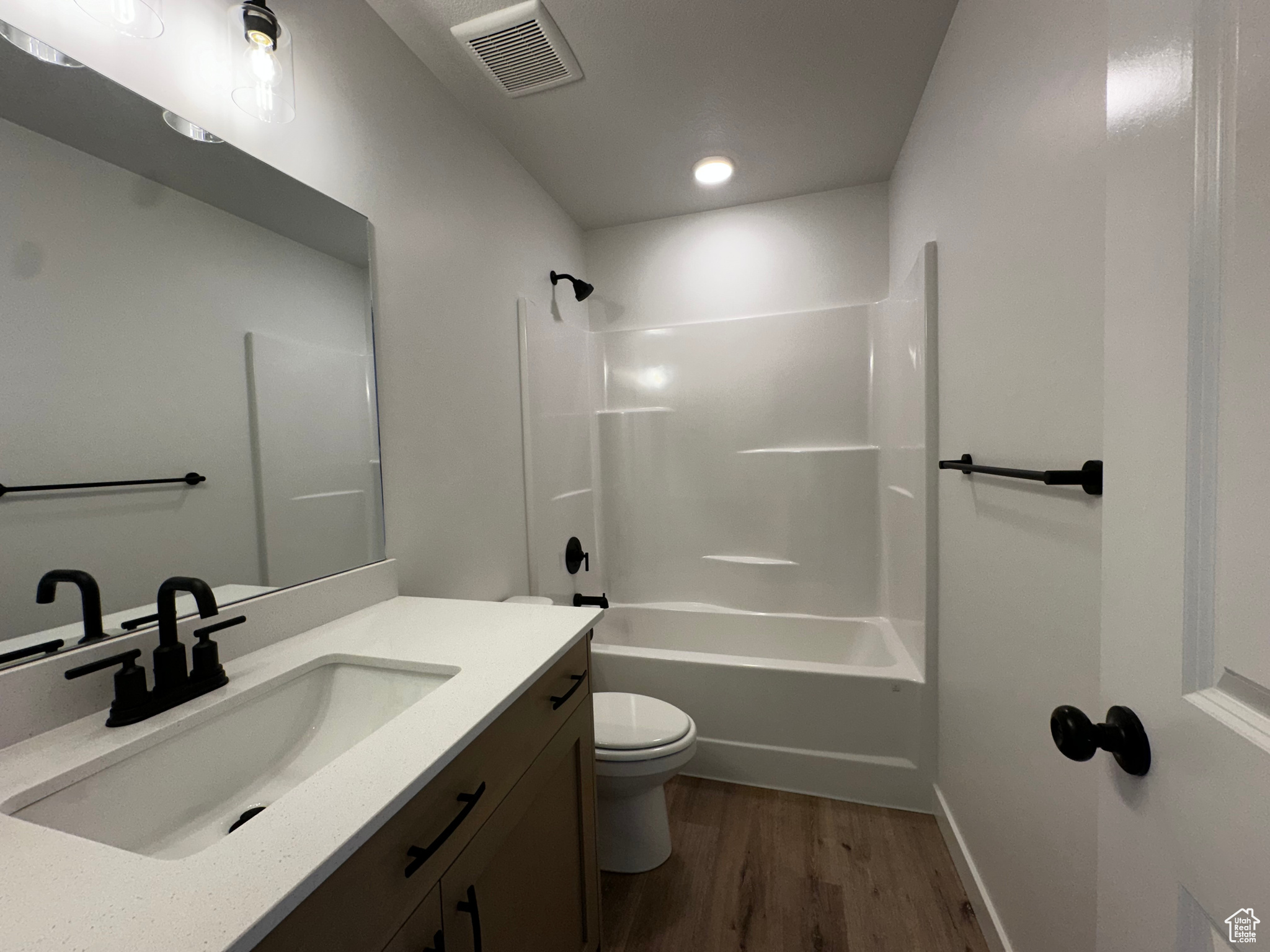 Full bathroom with wood-type flooring, shower / bathing tub combination, vanity, and toilet