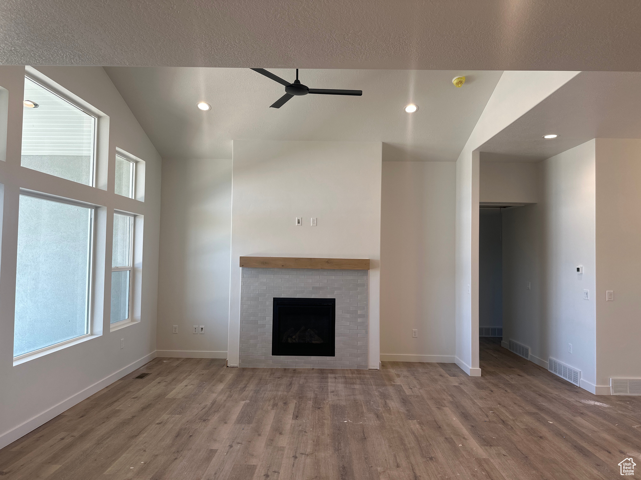 Unfurnished living room with ceiling fan, vaulted ceiling, and hardwood / wood-style flooring