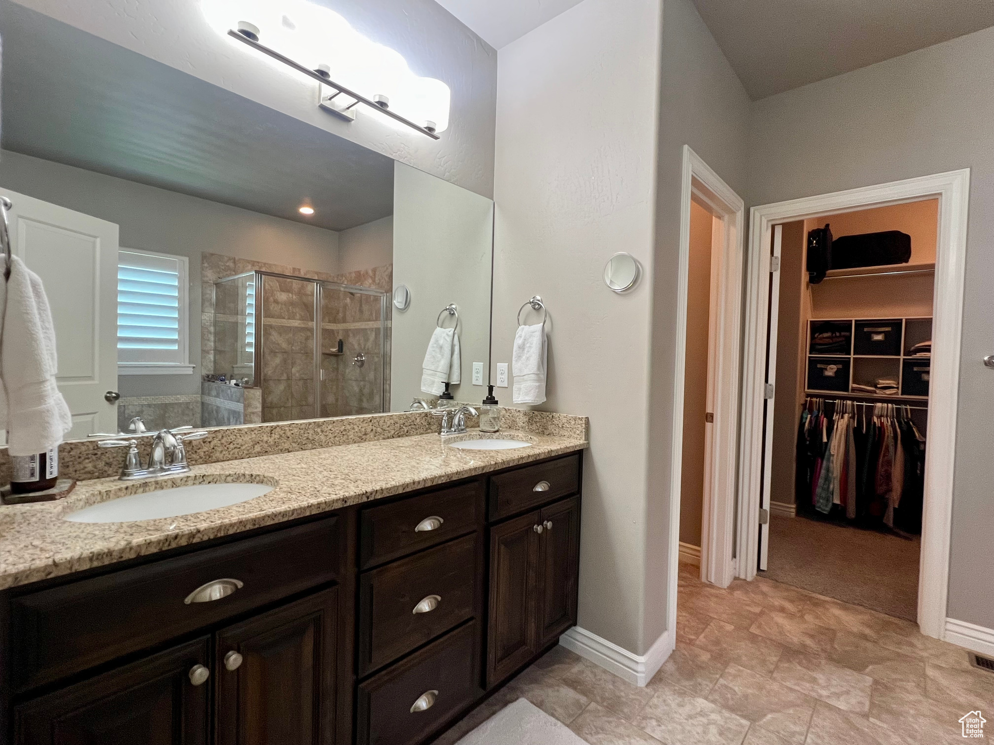Bathroom featuring a shower with door, tile floors, and double sink vanity