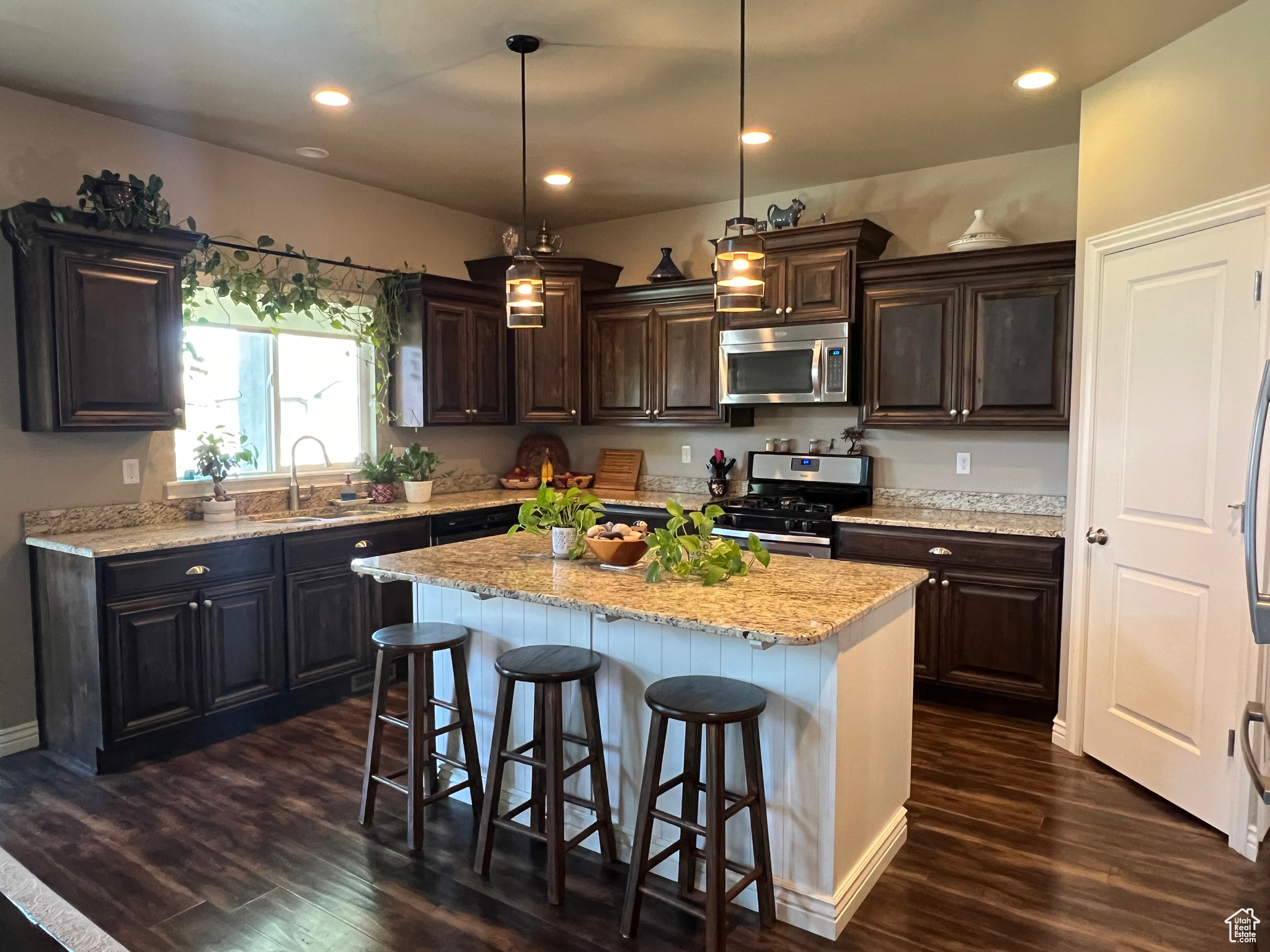 Kitchen with  island, sink, laminate hardwood / wood-style flooring, pendant lighting,  stainless steel appliances, granite countertops