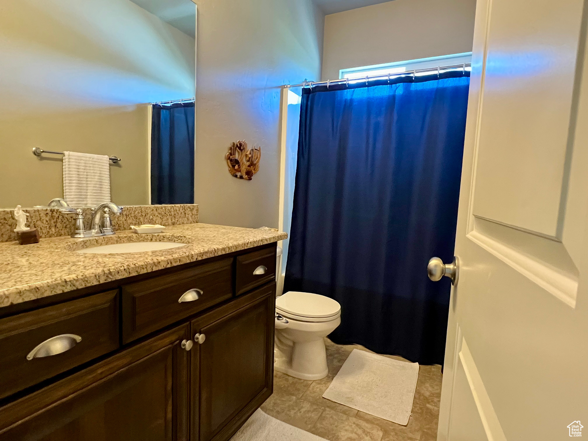 Bathroom featuring tile floors, vanity with granite counter tops , and toilet