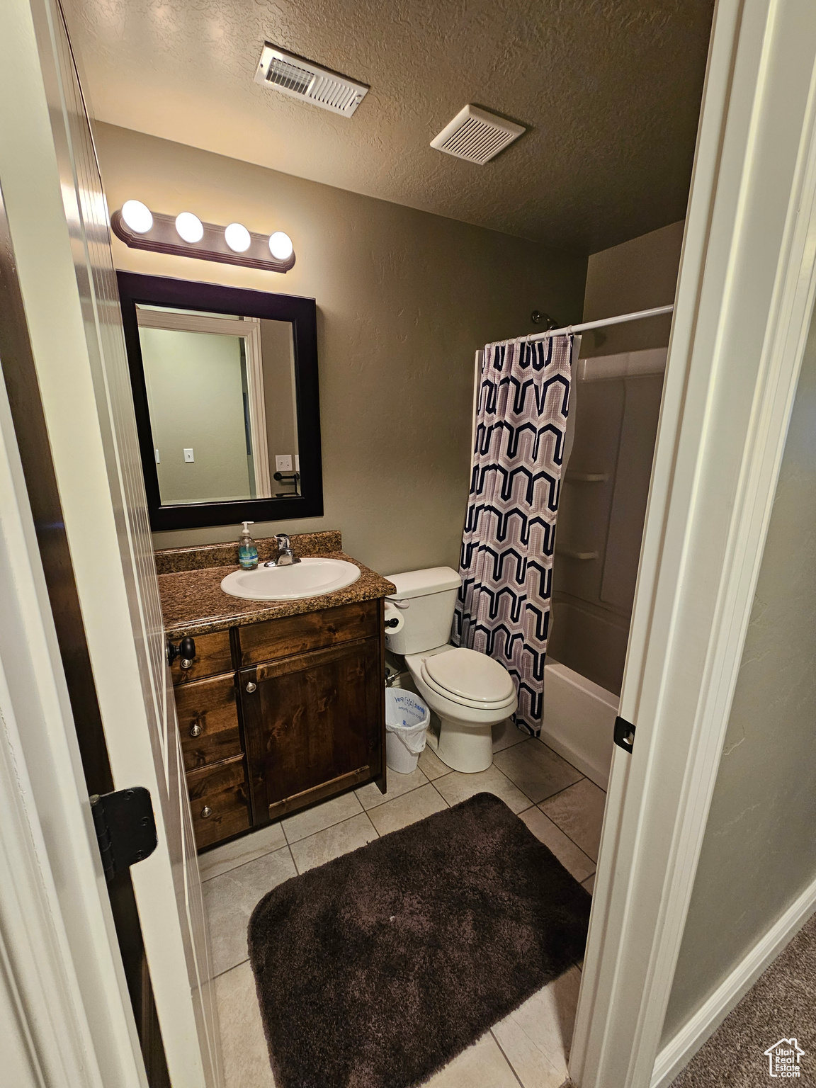 Full bathroom with vanity with extensive cabinet space, toilet, tile floors, and shower / bath combo with shower curtain