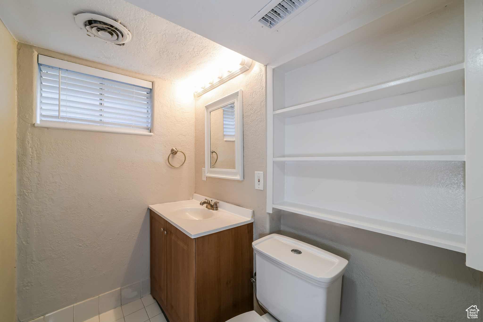 Bathroom featuring a textured ceiling, oversized vanity, toilet, and tile flooring