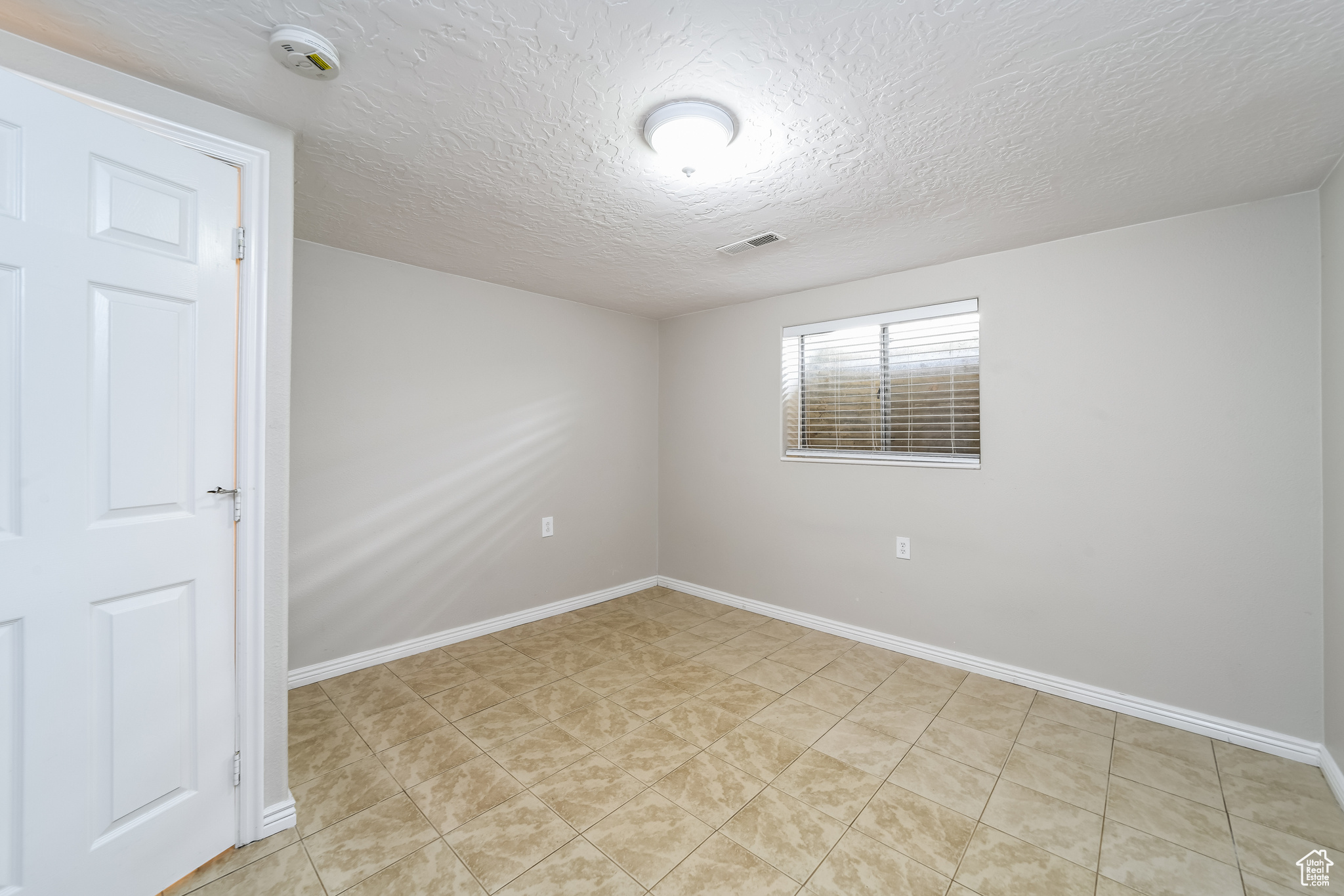 Unfurnished room with a textured ceiling and light tile floors