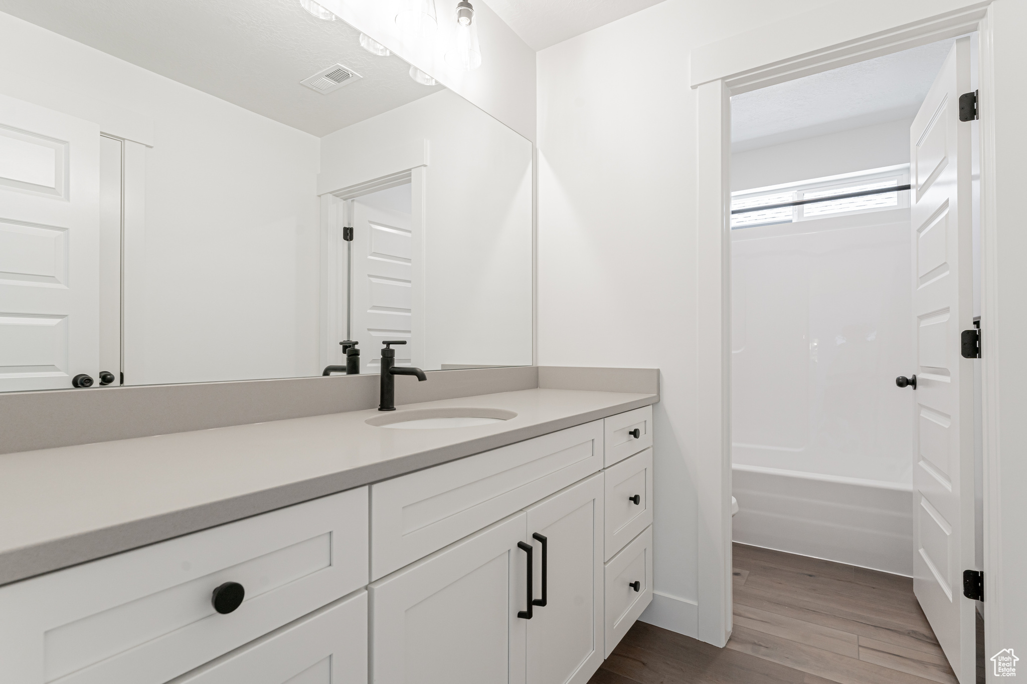 Bathroom featuring bathing tub / shower combination, hardwood / wood-style floors, and vanity