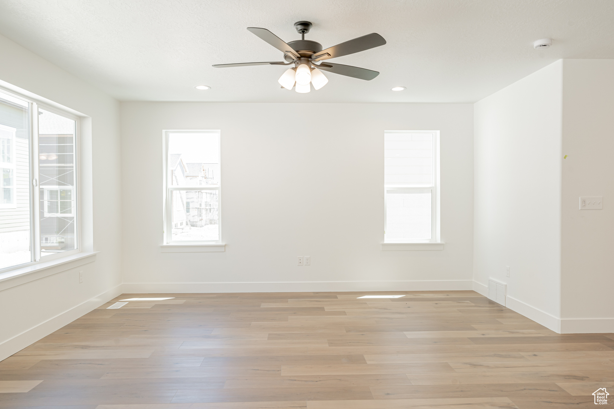 Spare room with ceiling fan, light hardwood / wood-style floors, and plenty of natural light