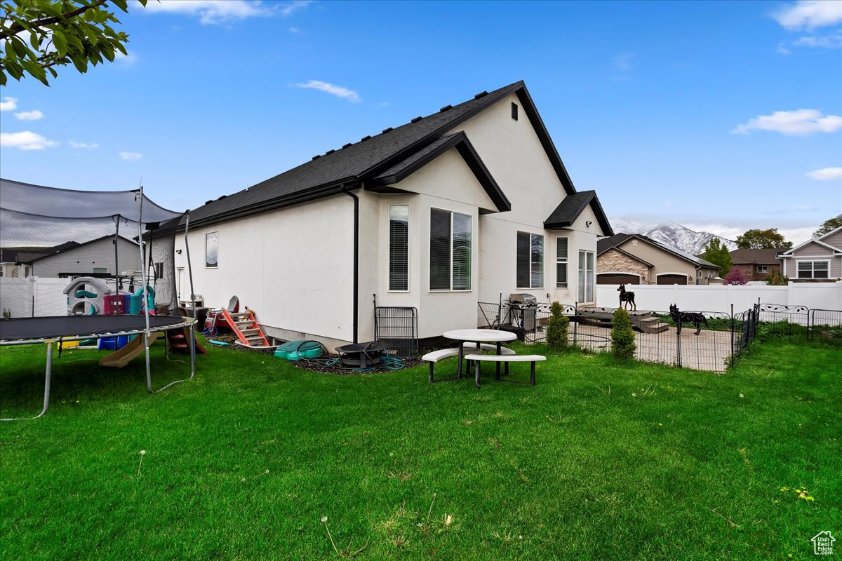 Rear view of property with a trampoline and a lawn