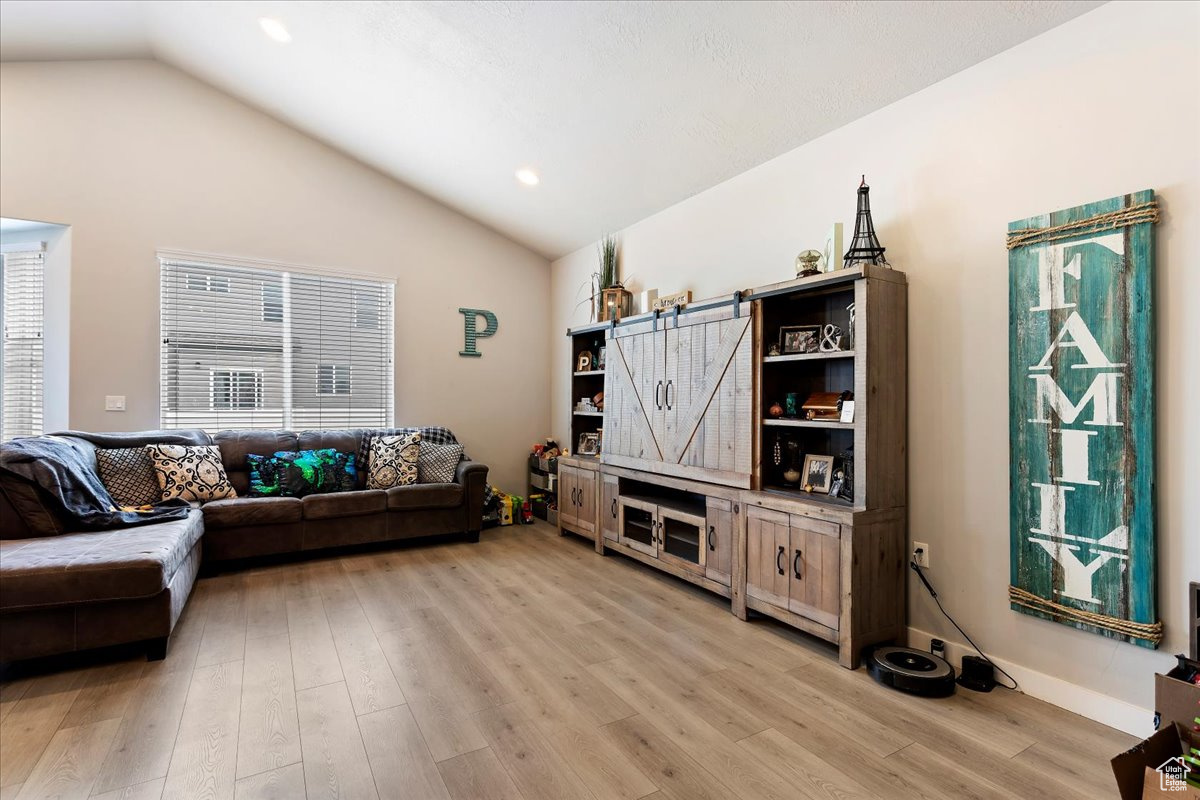 Living room with lofted ceiling and light hardwood / wood-style flooring