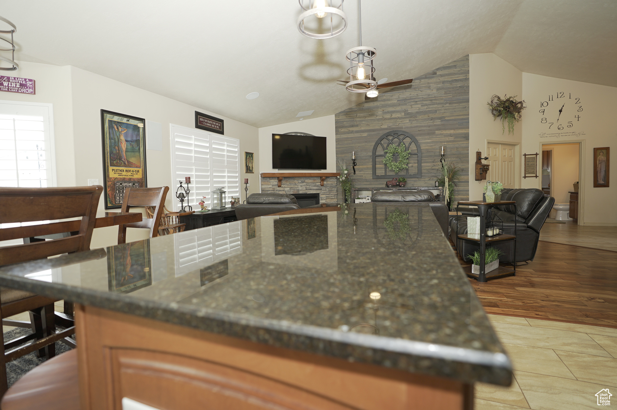 Kitchen with pendant lighting, tile flooring, a stone fireplace, dark stone counters, and ceiling fan
