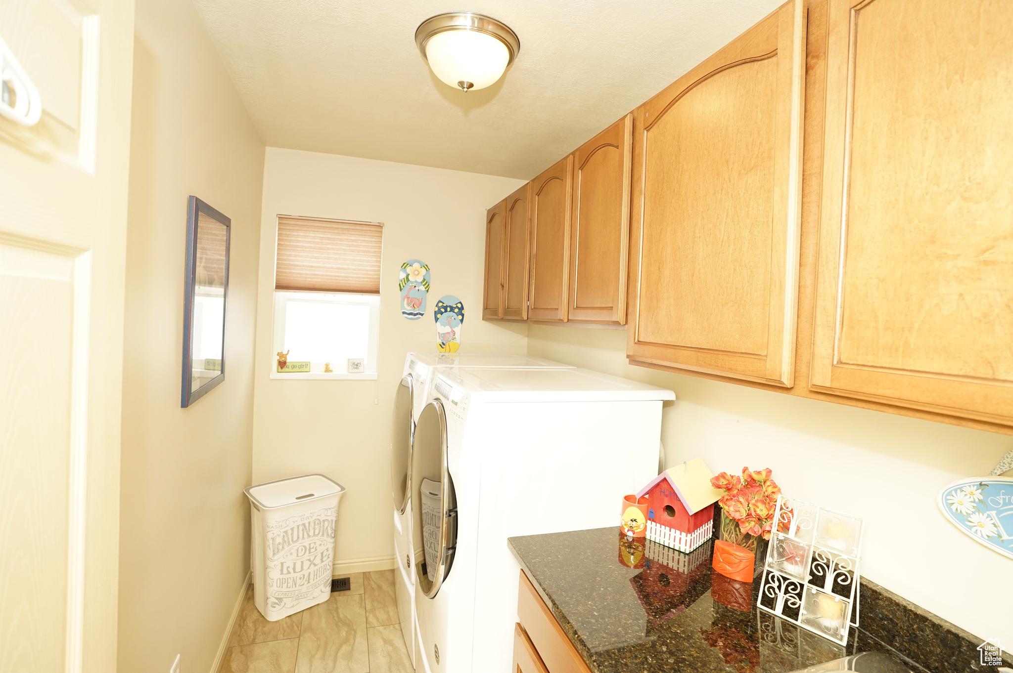 Laundry room with cabinets, light tile flooring, and washer and dryer