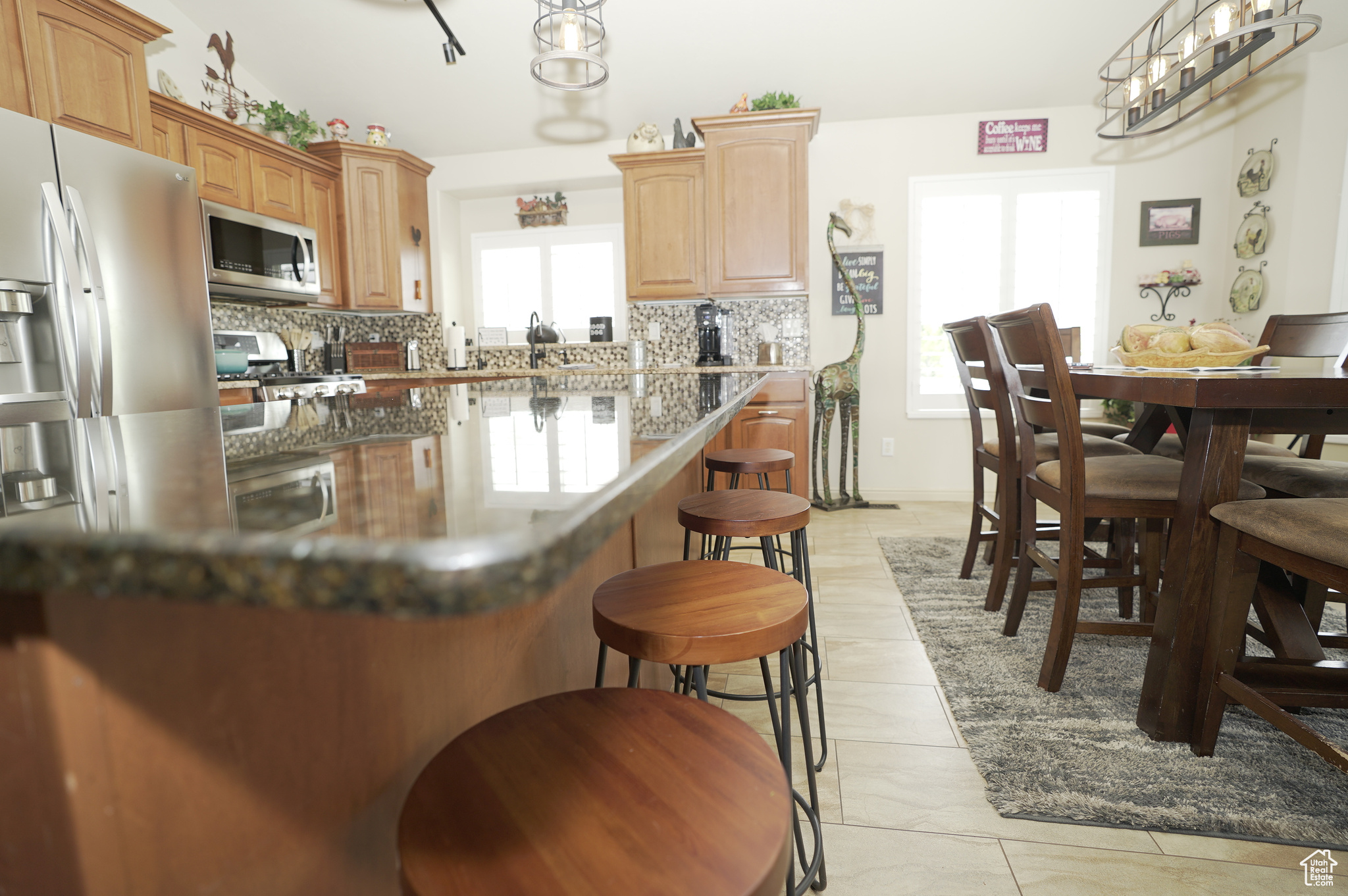 Kitchen featuring backsplash, stainless steel appliances, light tile floors, and a kitchen bar