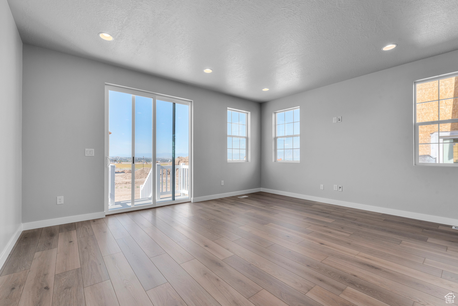 Unfurnished room with a wealth of natural light, hardwood / wood-style floors, and a textured ceiling