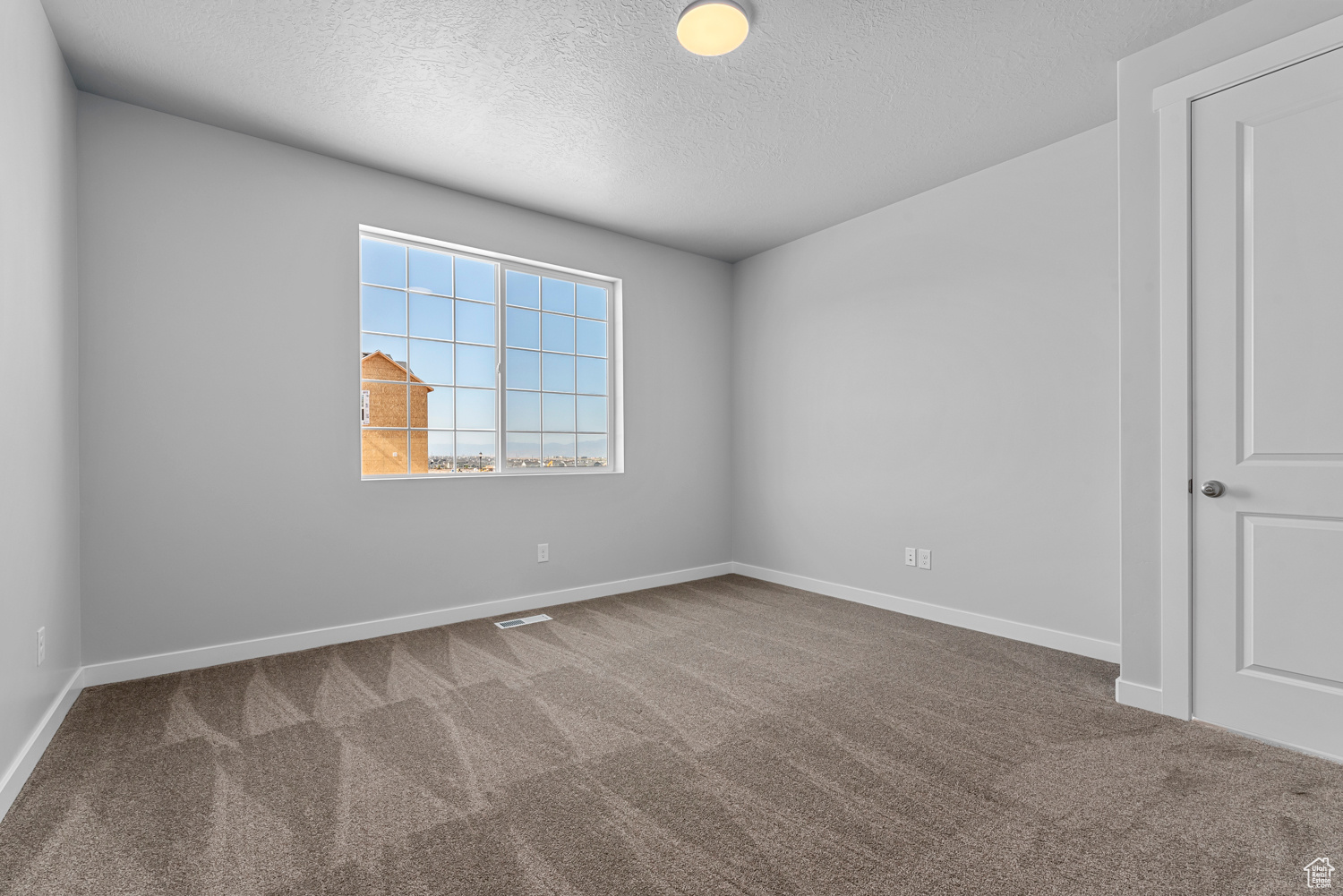 Carpeted spare room with a textured ceiling