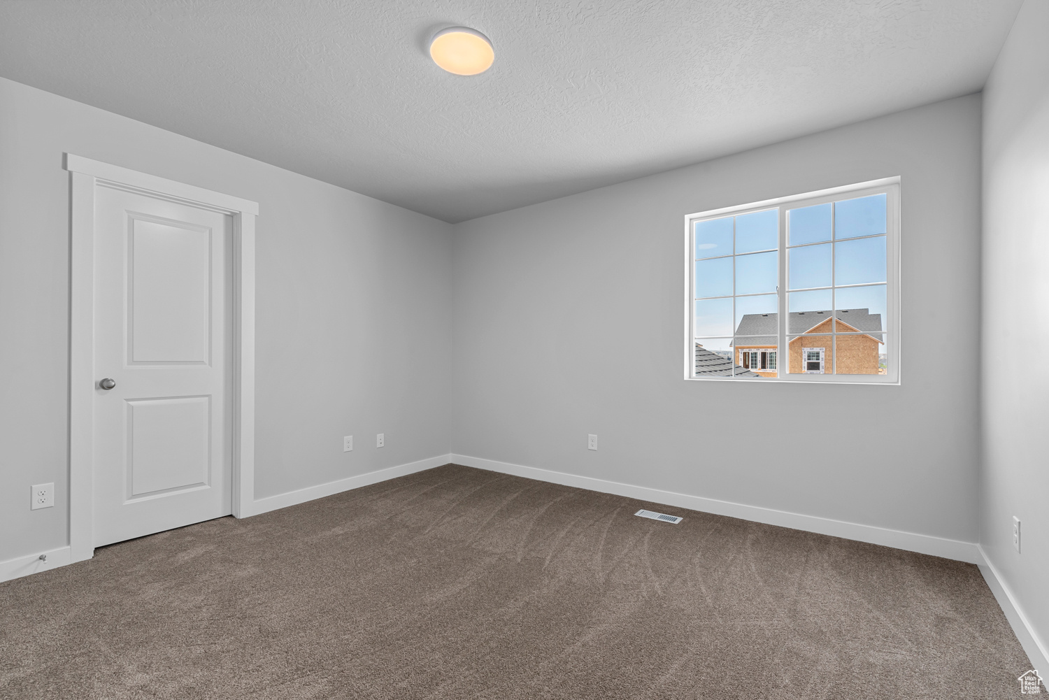 Carpeted spare room with a textured ceiling