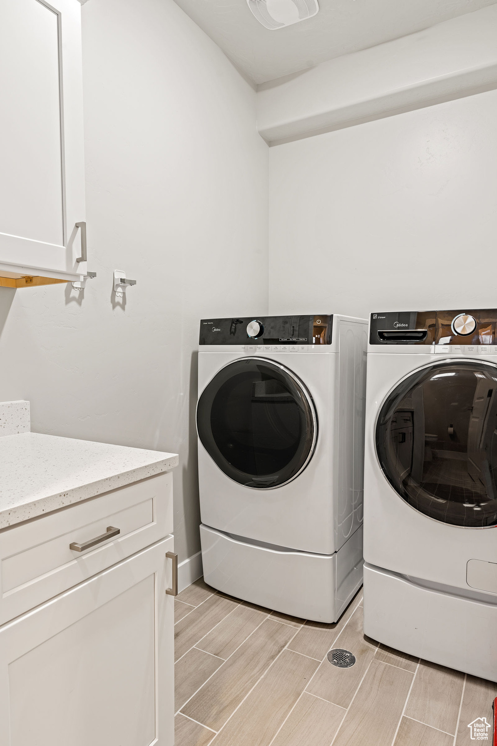 Clothes washing area with cabinets, light hardwood / wood-style floors, and washer and clothes dryer