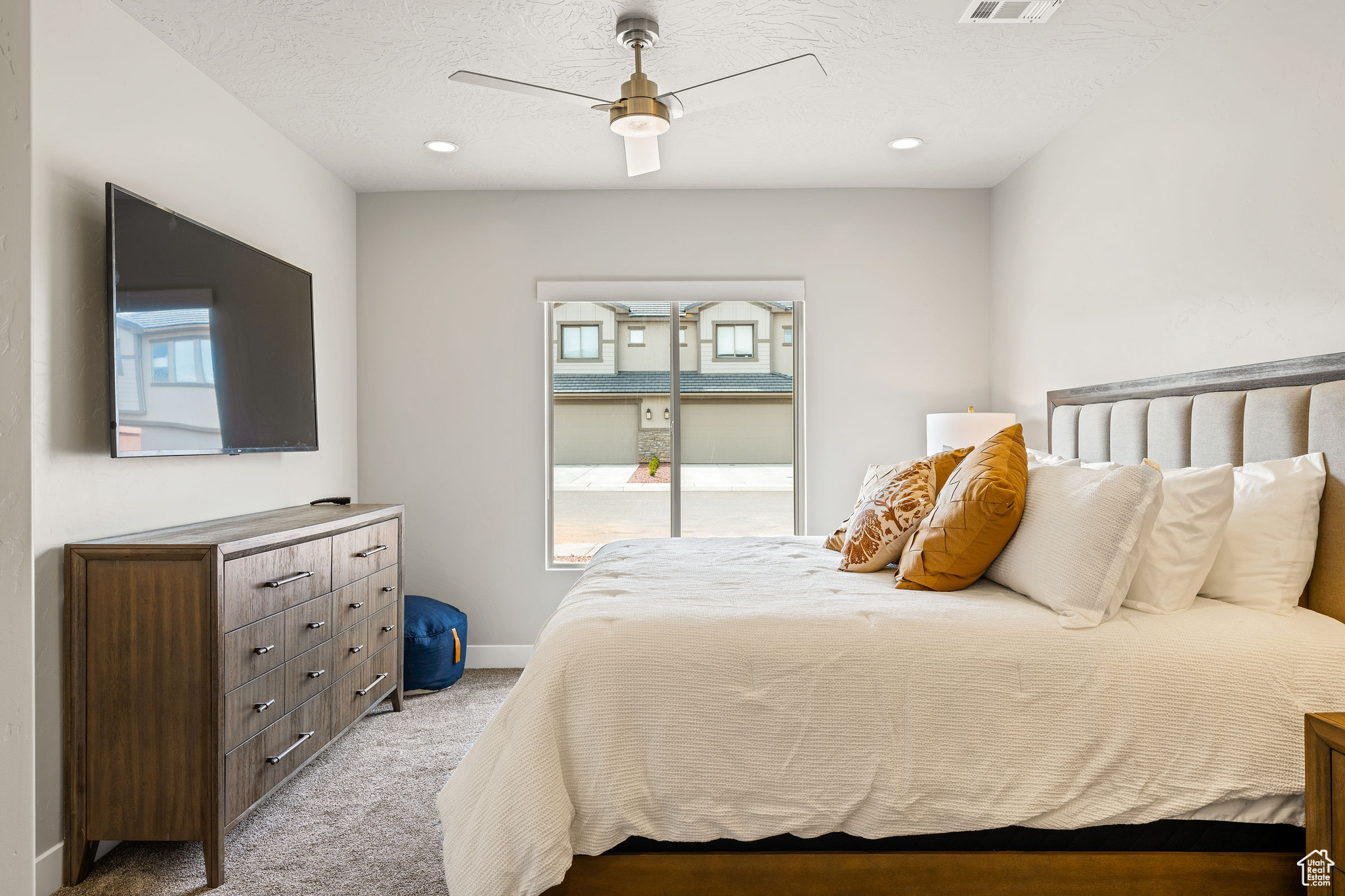 Bedroom with light carpet, ceiling fan, and a textured ceiling