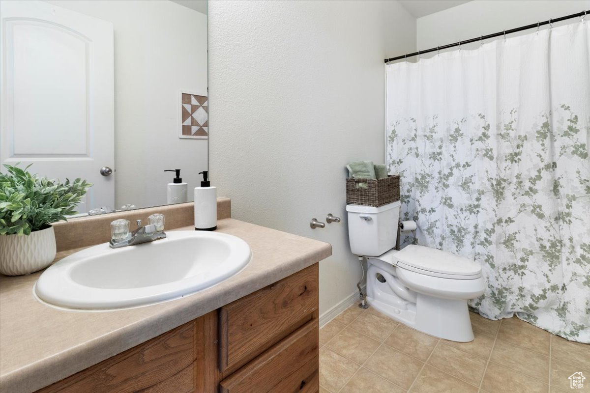 Bathroom featuring vanity with extensive cabinet space, toilet, and tile flooring
