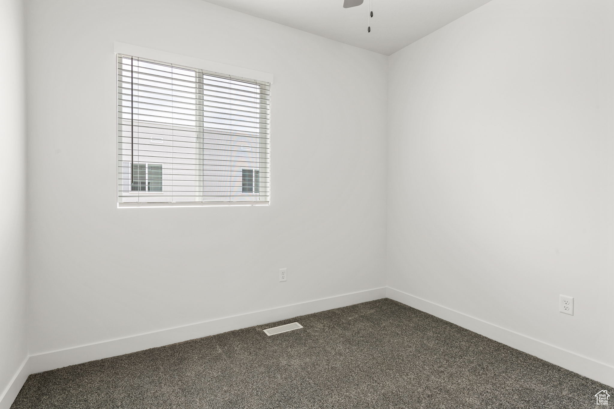 Empty room with dark colored carpet and ceiling fan