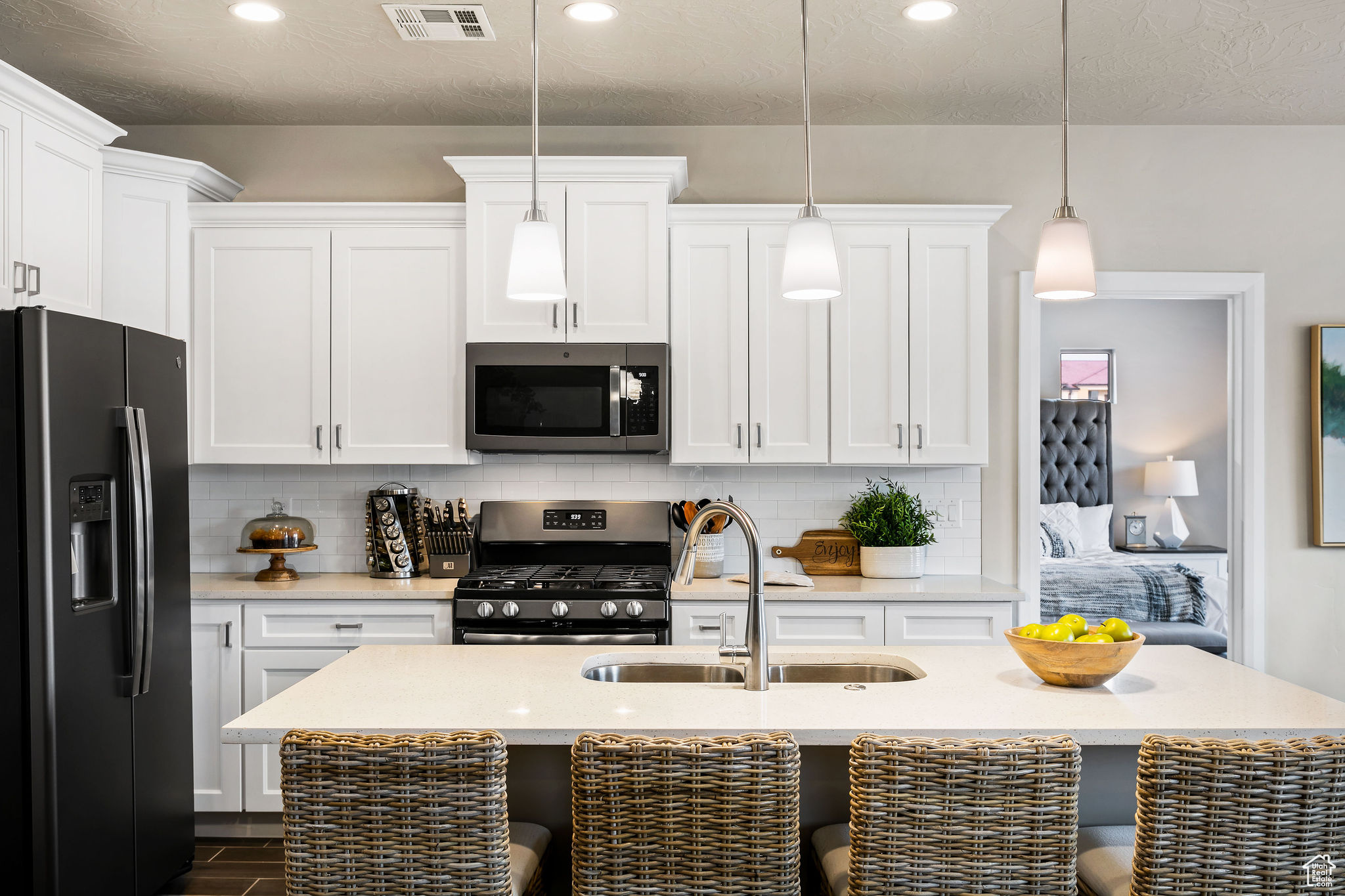Kitchen featuring stainless steel appliances, a center island with sink, tasteful backsplash, sink, and pendant lighting