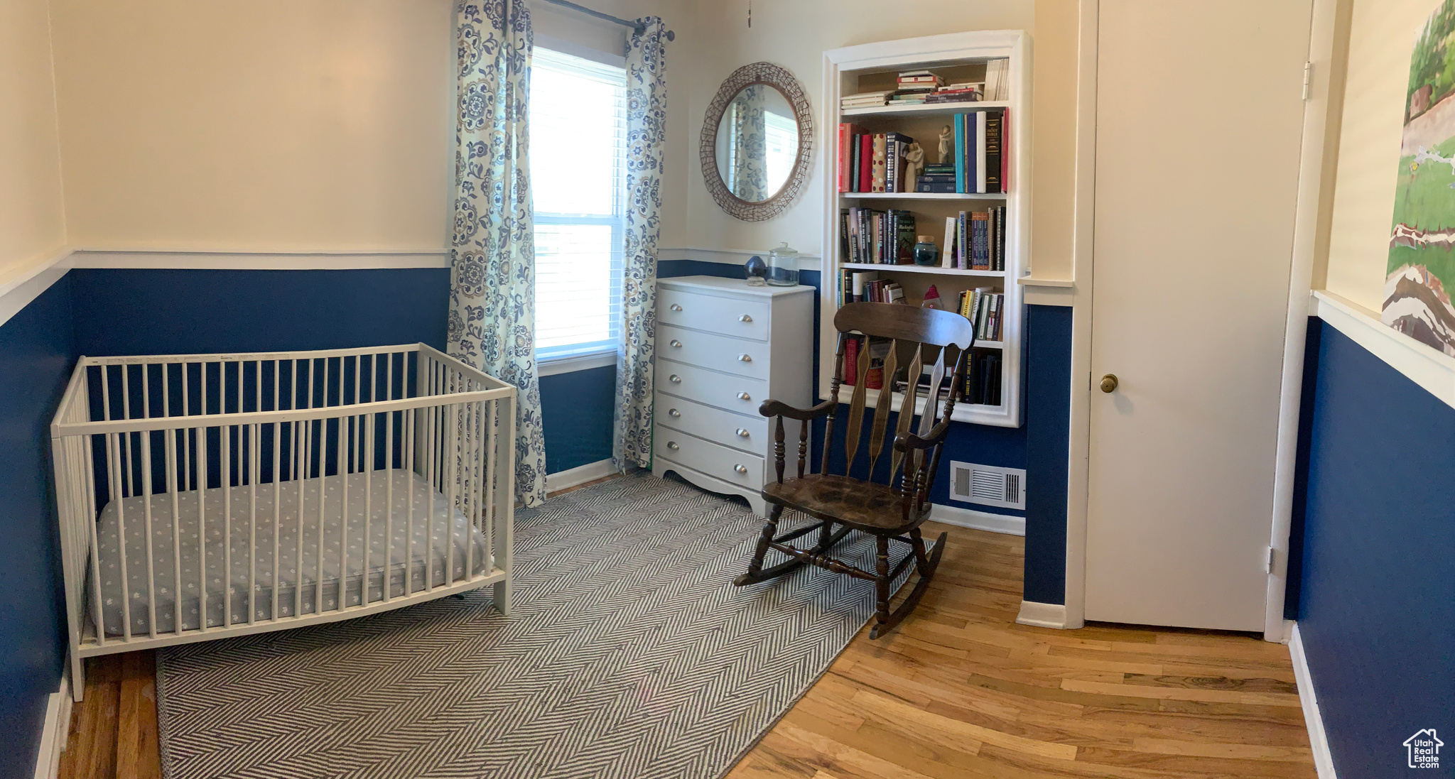Bedroom featuring wood-type flooring and a nursery area