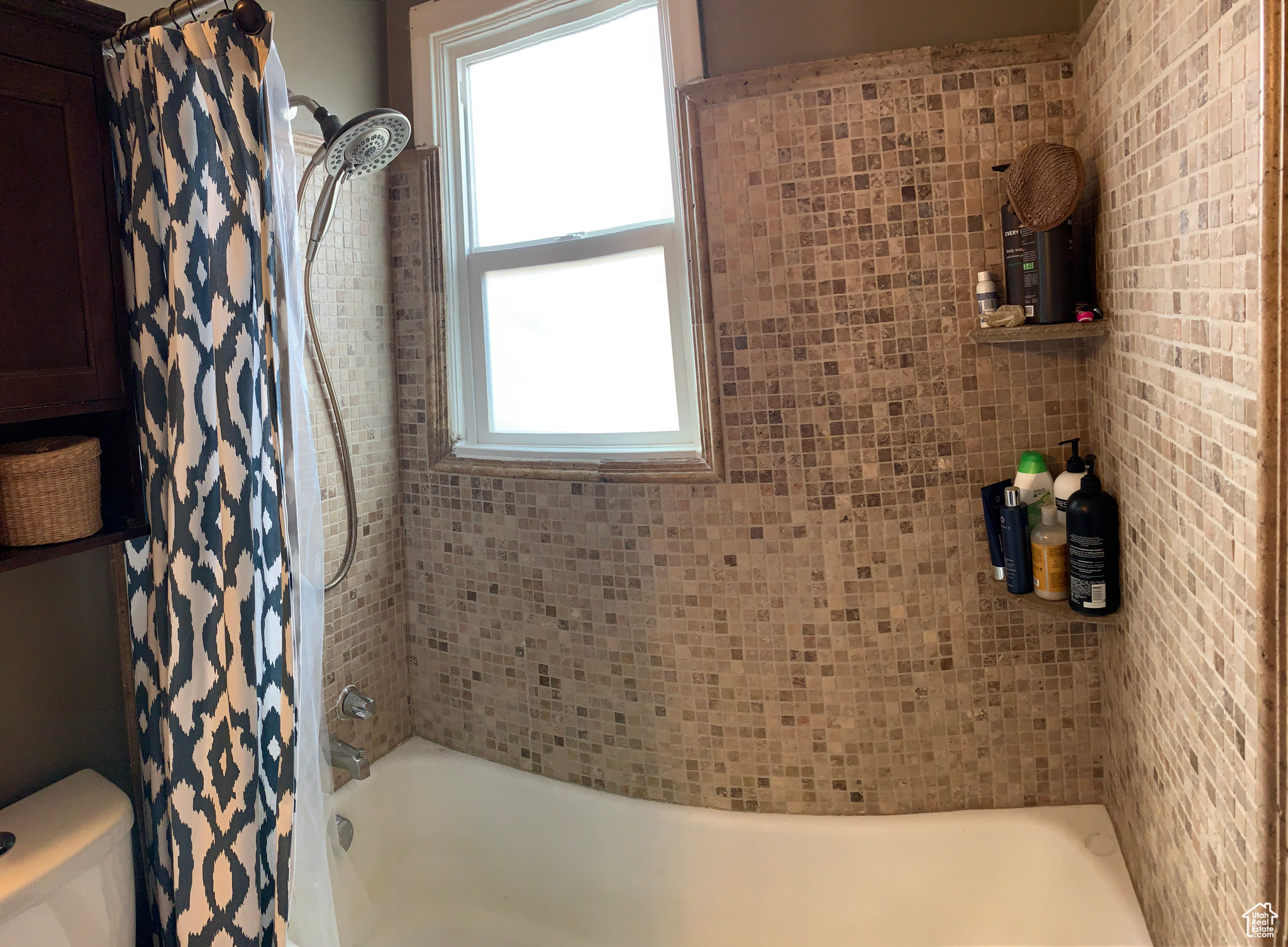 Bathroom featuring plenty of natural light, shower / tub combo, and toilet
