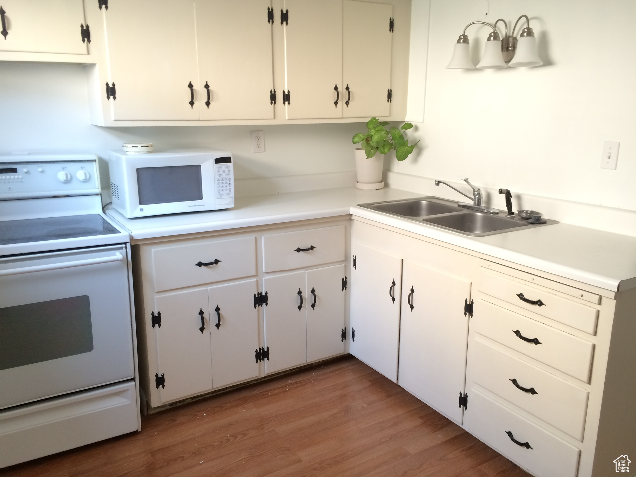 Kitchen with wood-type flooring, white appliances, white cabinetry, and sink