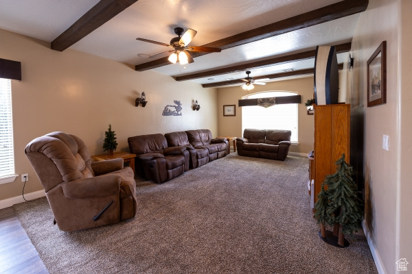 Living room featuring hardwood / wood-style flooring, beamed ceiling, and ceiling fan