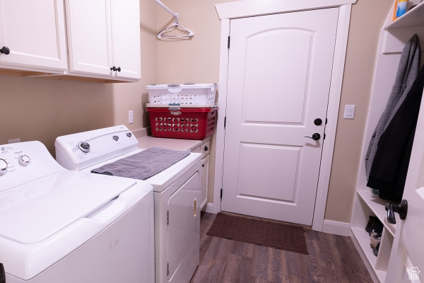 Clothes washing area featuring dark hardwood / wood-style floors, cabinets, and washer and clothes dryer