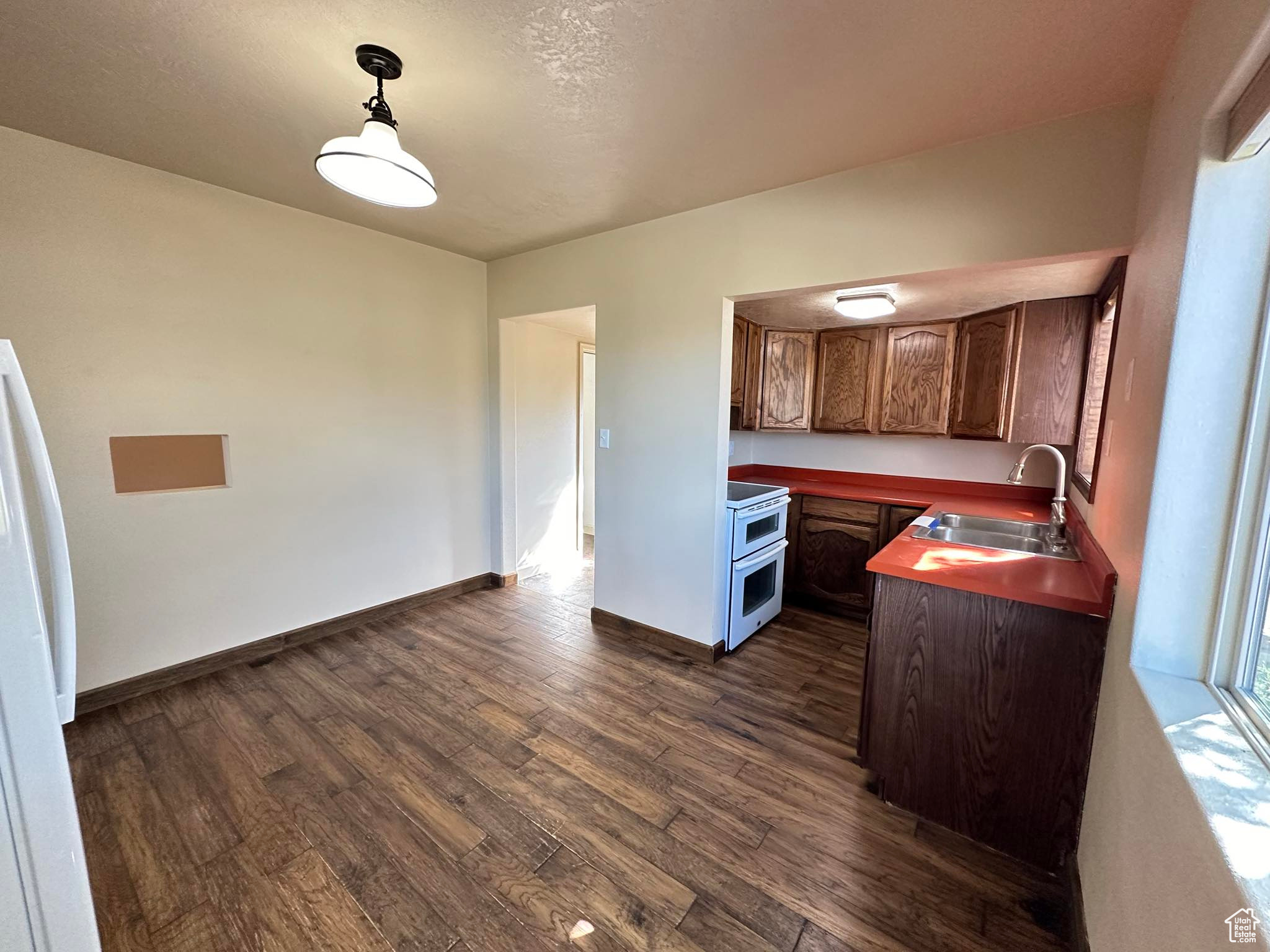 Kitchen with dark hardwood / wood-style floors, sink, decorative light fixtures, and range with two ovens