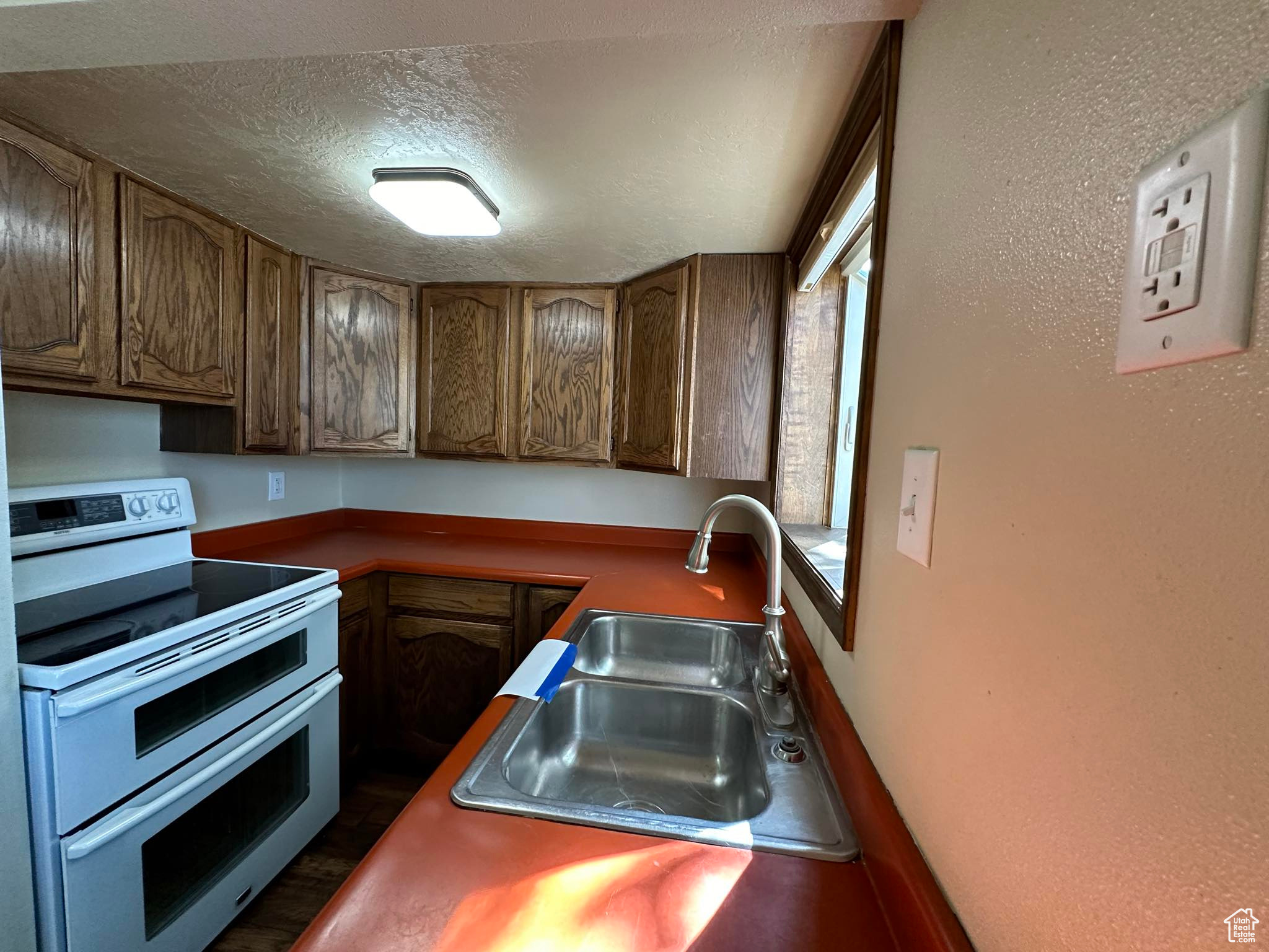 Kitchen with range with two ovens, a textured ceiling, and sink