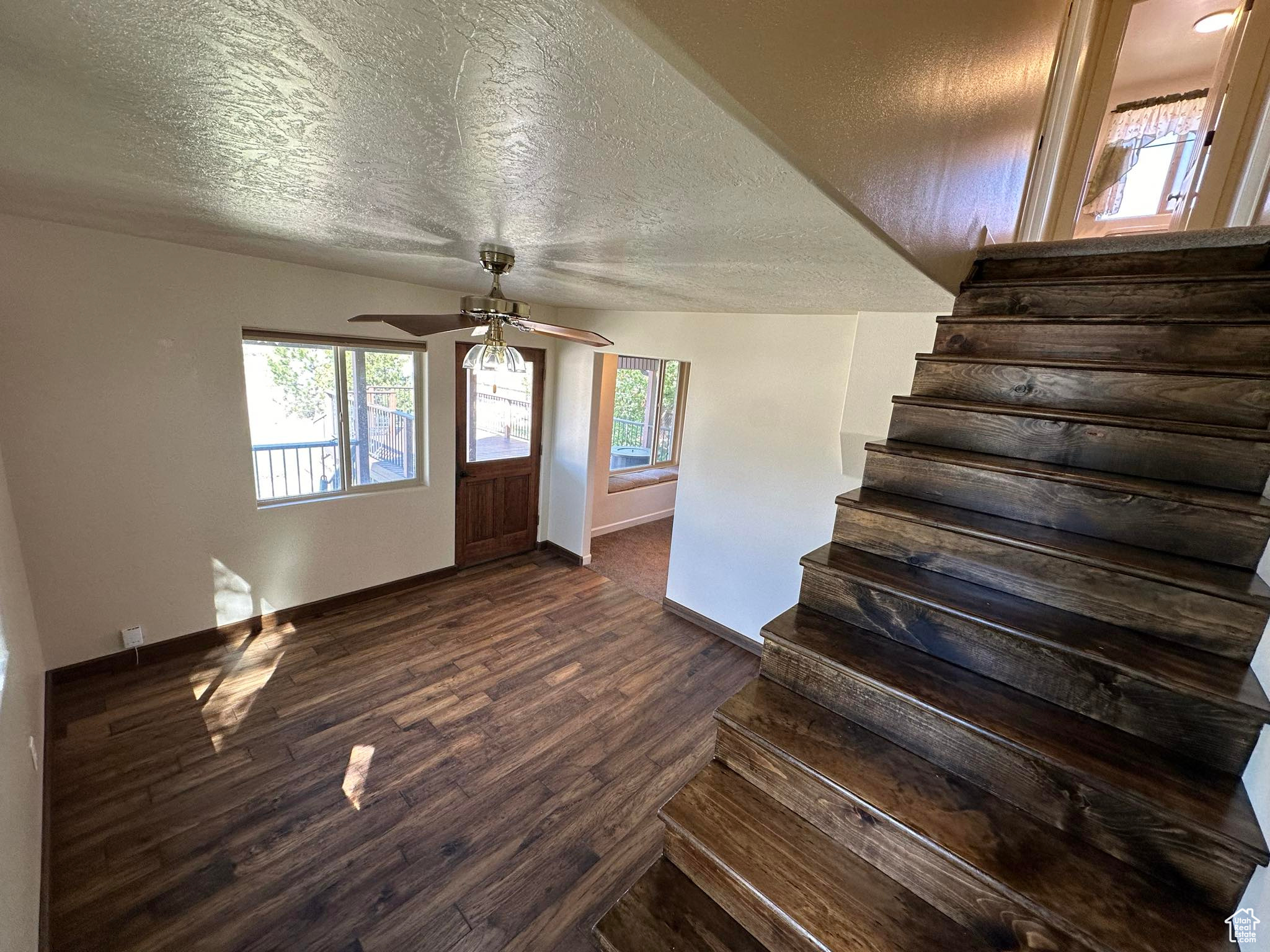 Entrance foyer with ceiling fan, dark hardwood / wood-style floors, and a textured ceiling