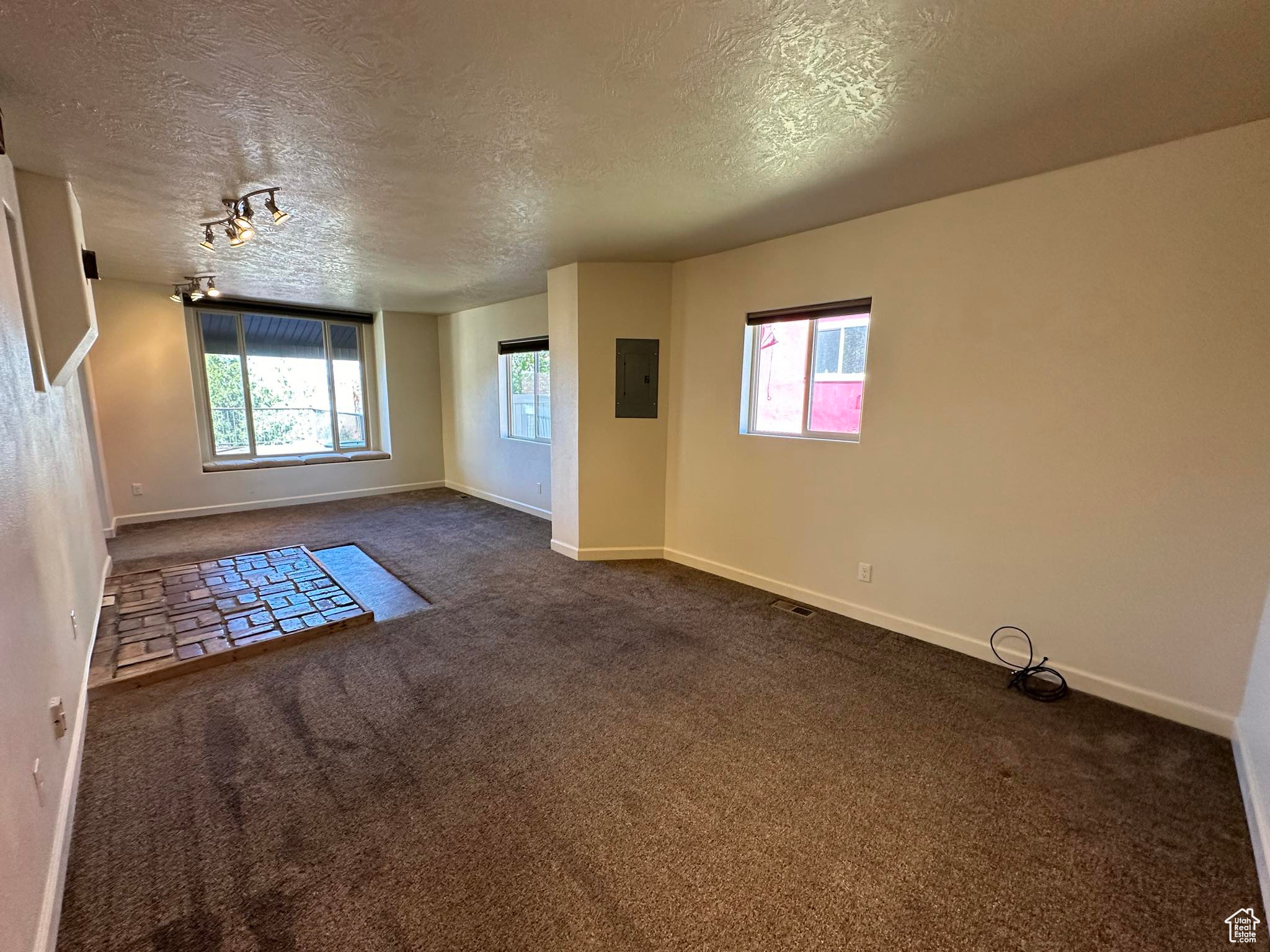 Spare room featuring dark colored carpet and a textured ceiling