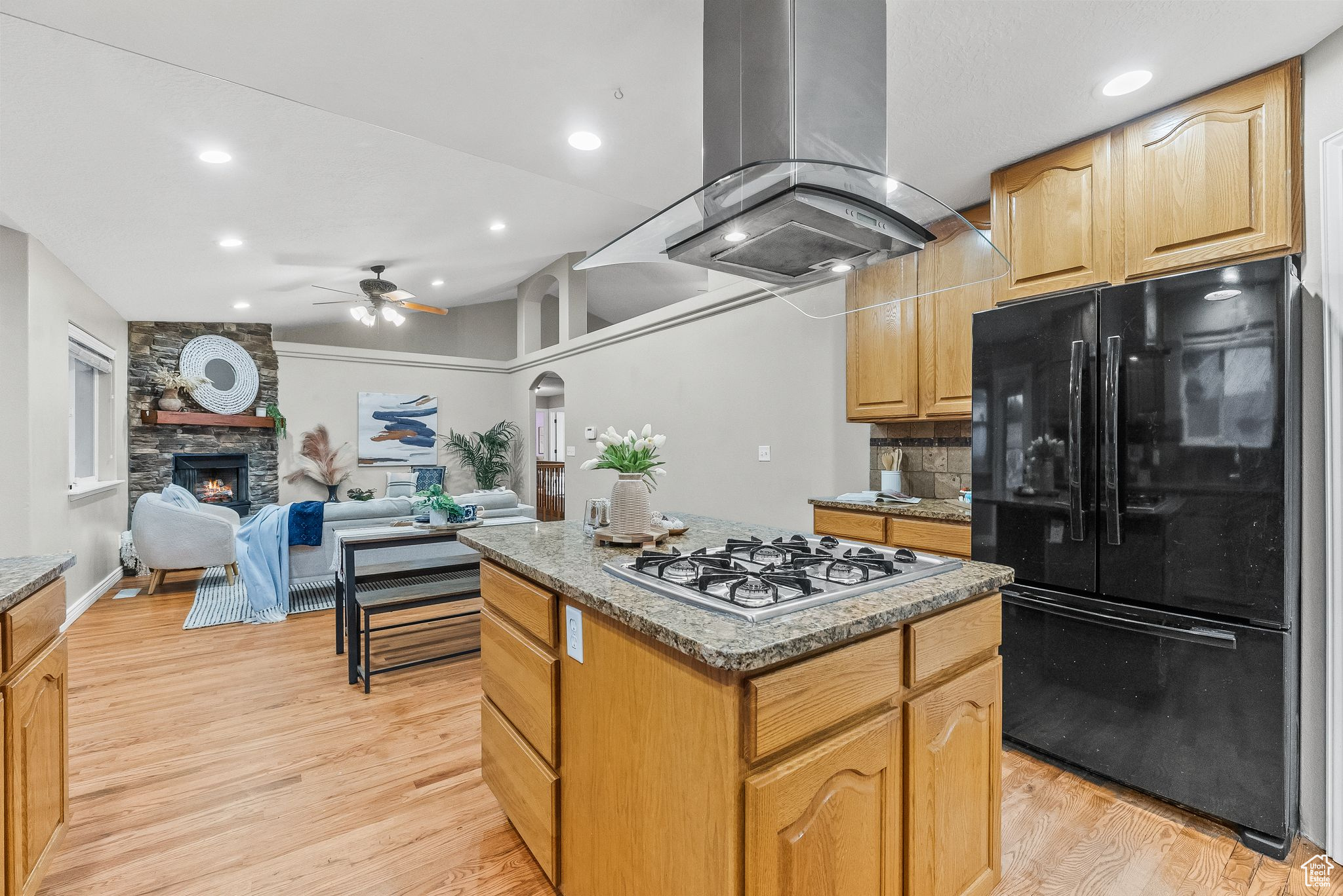 Kitchen featuring a center island, black fridge, light hardwood / wood-style flooring, island range hood, and ceiling fan
