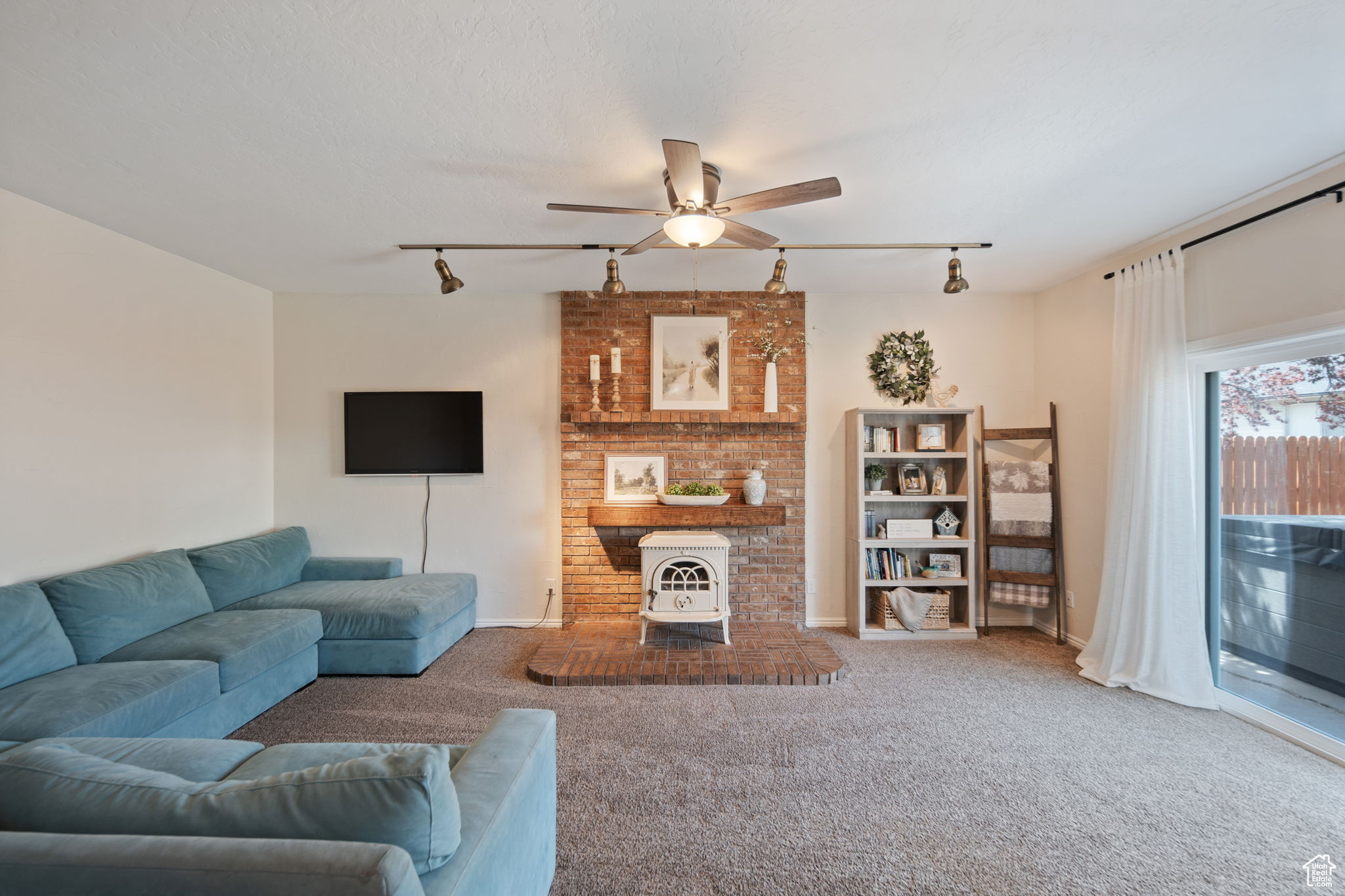 Living room with ceiling fan, track lighting, and carpet floors