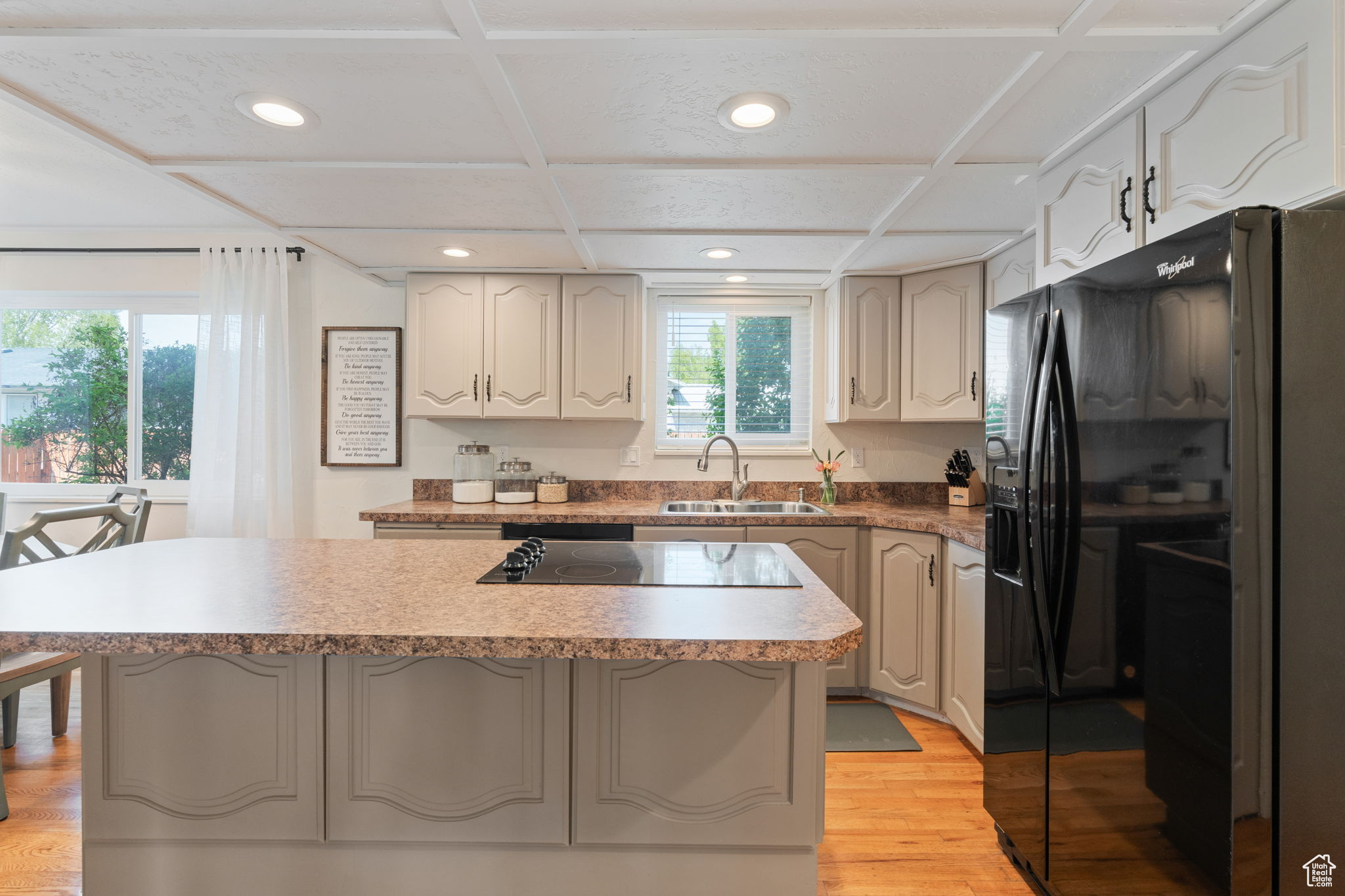 Kitchen featuring a kitchen island, sink, black appliances, light hardwood / wood-style flooring, and a kitchen breakfast bar
