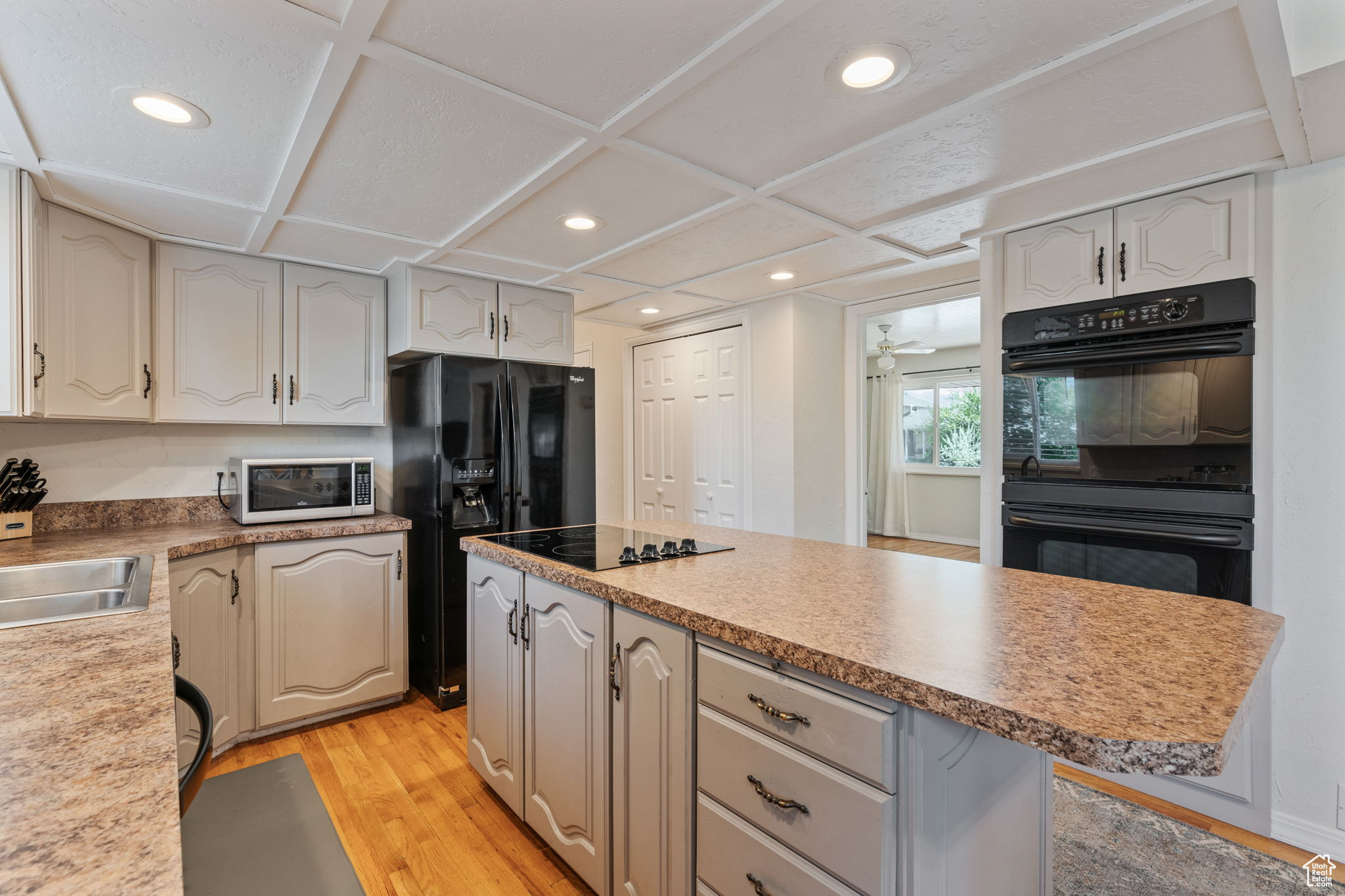 Kitchen featuring a center island, black appliances, sink, a kitchen bar, and light hardwood / wood-style floors