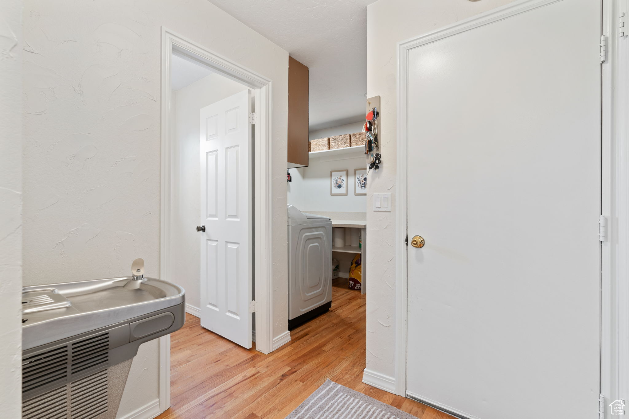 Corridor featuring light hardwood / wood-style flooring and washer / dryer, drinking fountain