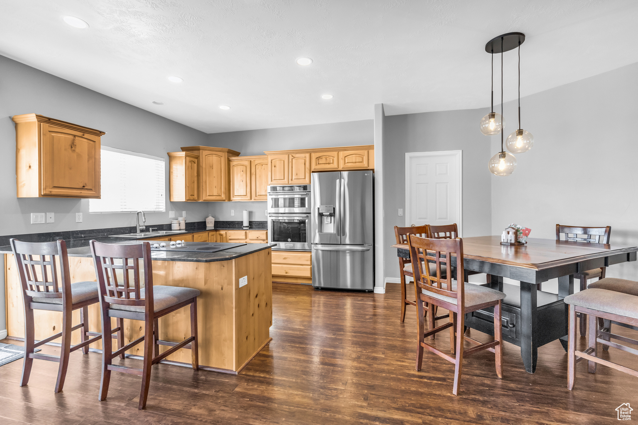 Kitchen featuring decorative light fixtures, a kitchen island, stainless steel appliances, dark hardwood / wood-style flooring, and a breakfast bar