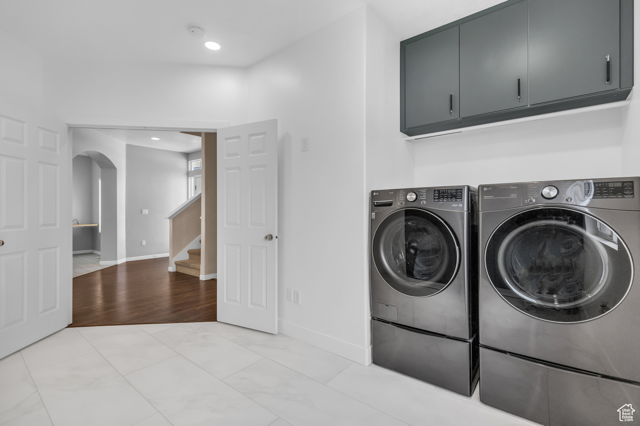 Clothes washing area with cabinets, independent washer and dryer, and light tile floors