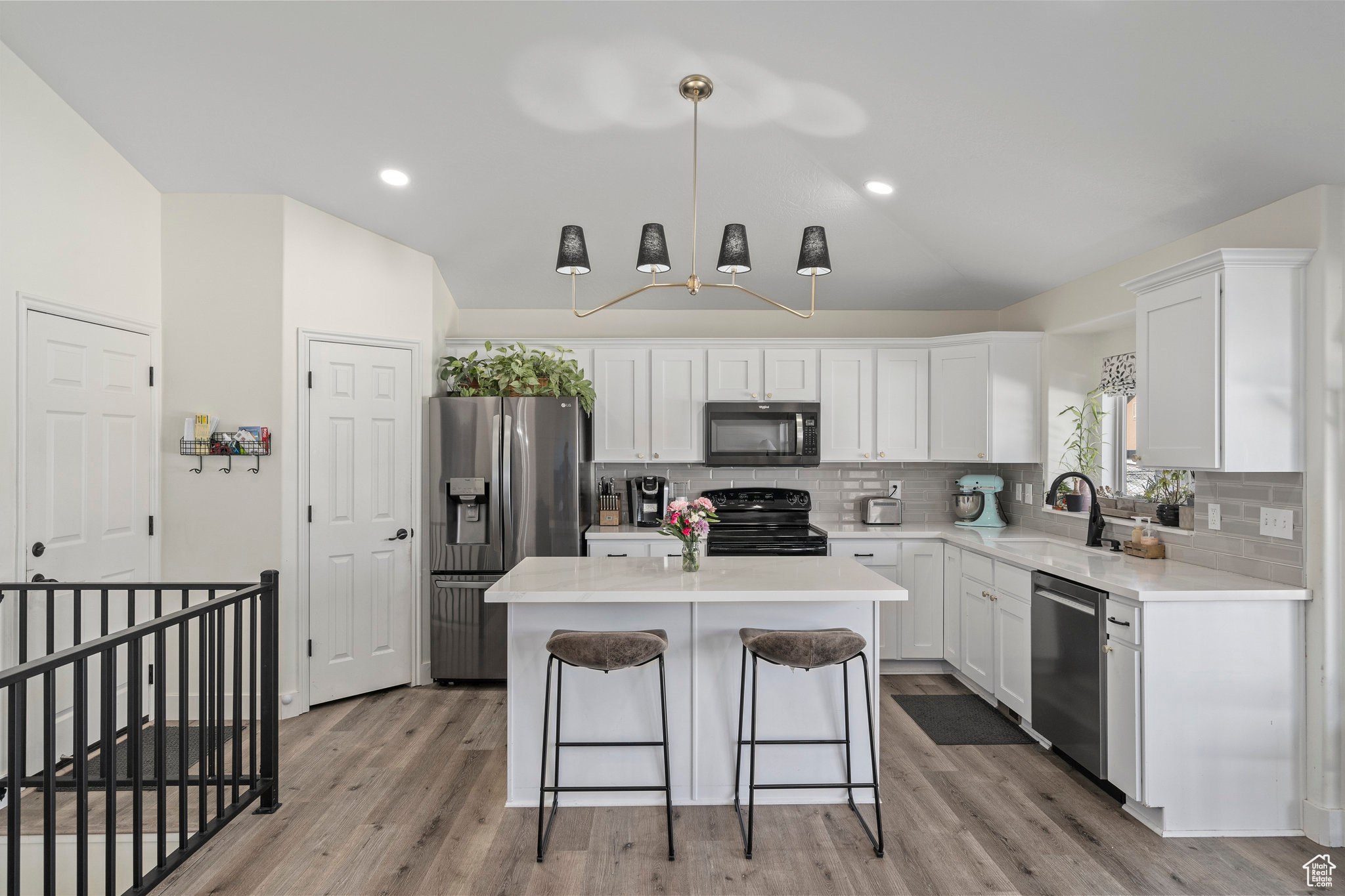 Kitchen with decorative light fixtures, stainless steel appliances, wood-style floors, a center island, and decorative  lighting