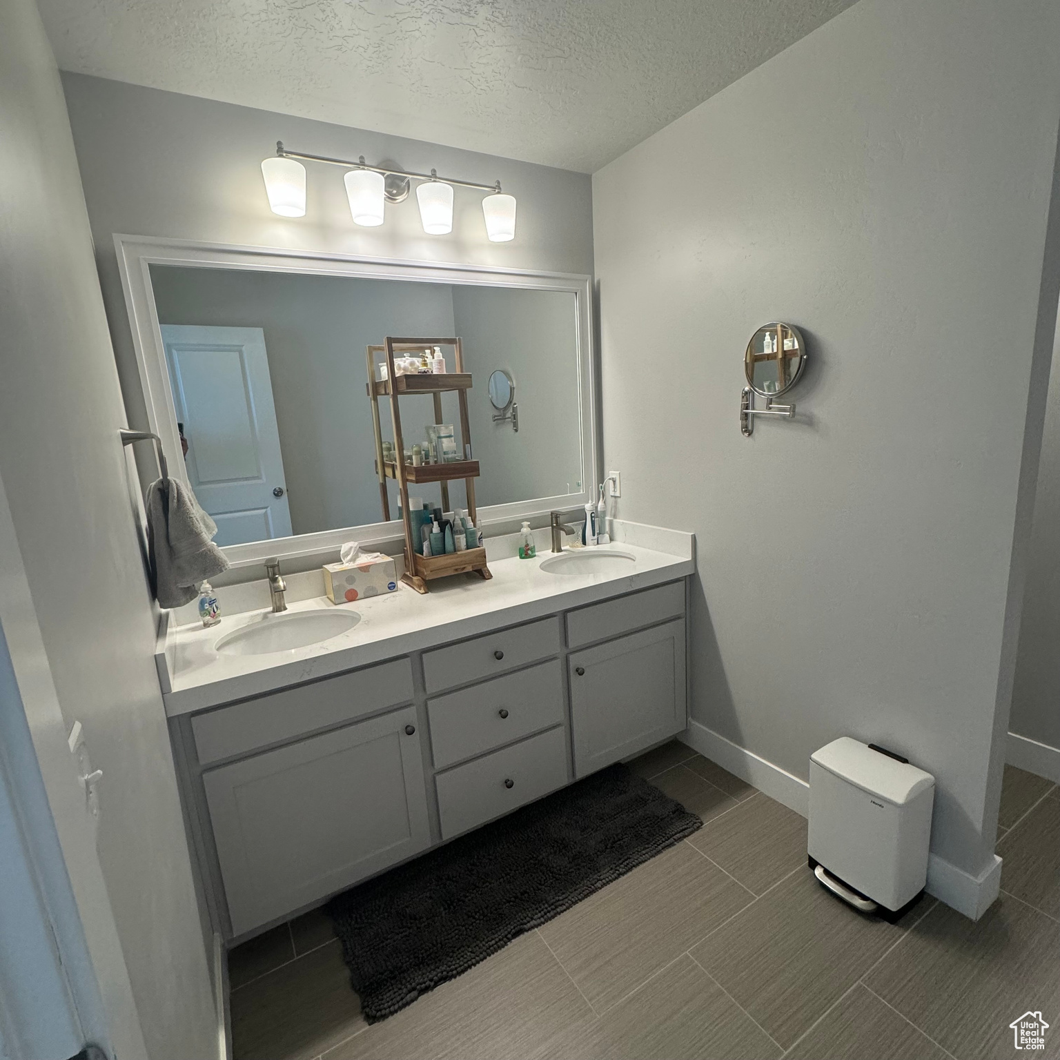 Bathroom featuring a textured ceiling, dual vanity, and tile flooring