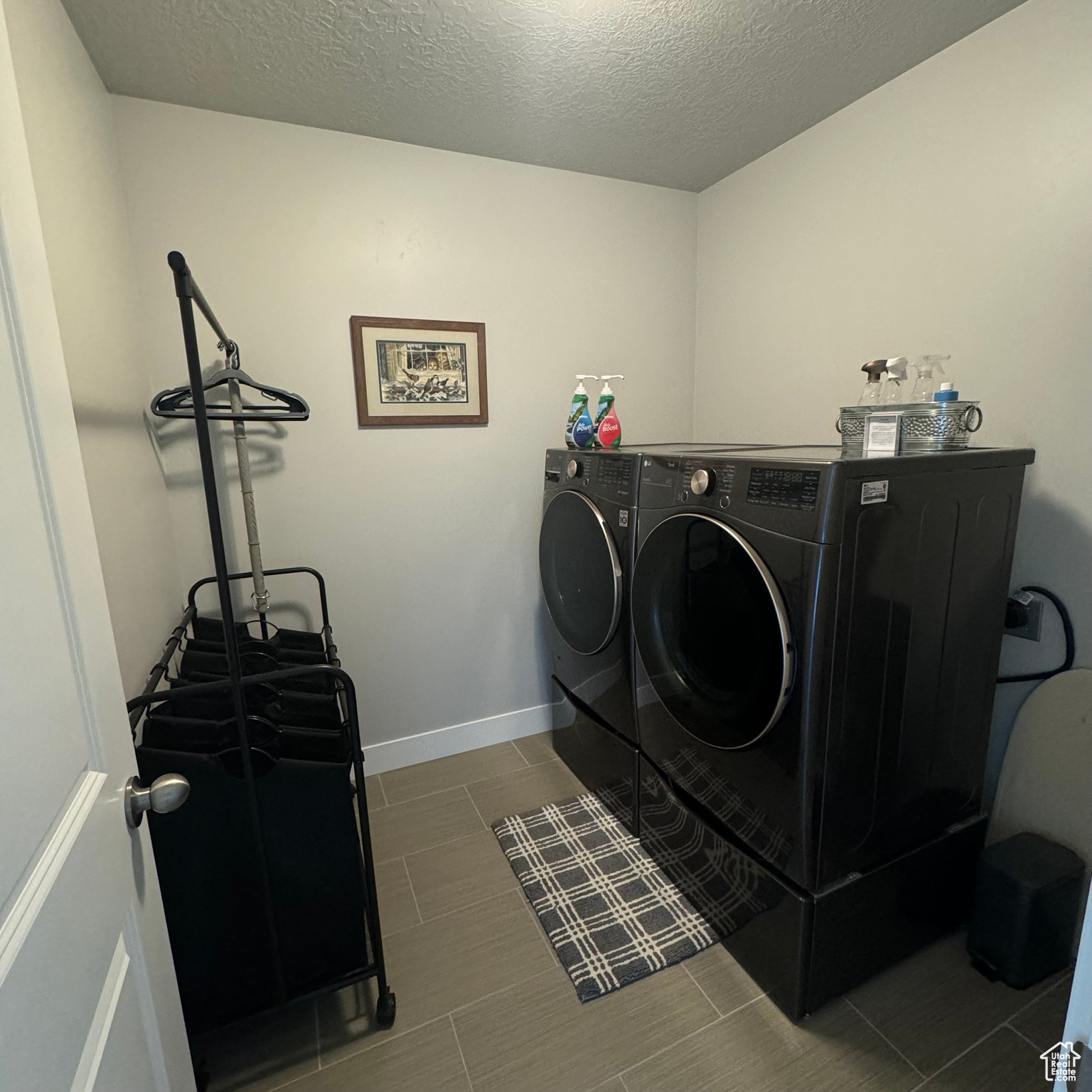 Clothes washing area featuring washing machine and dryer, tile floors, and a textured ceiling