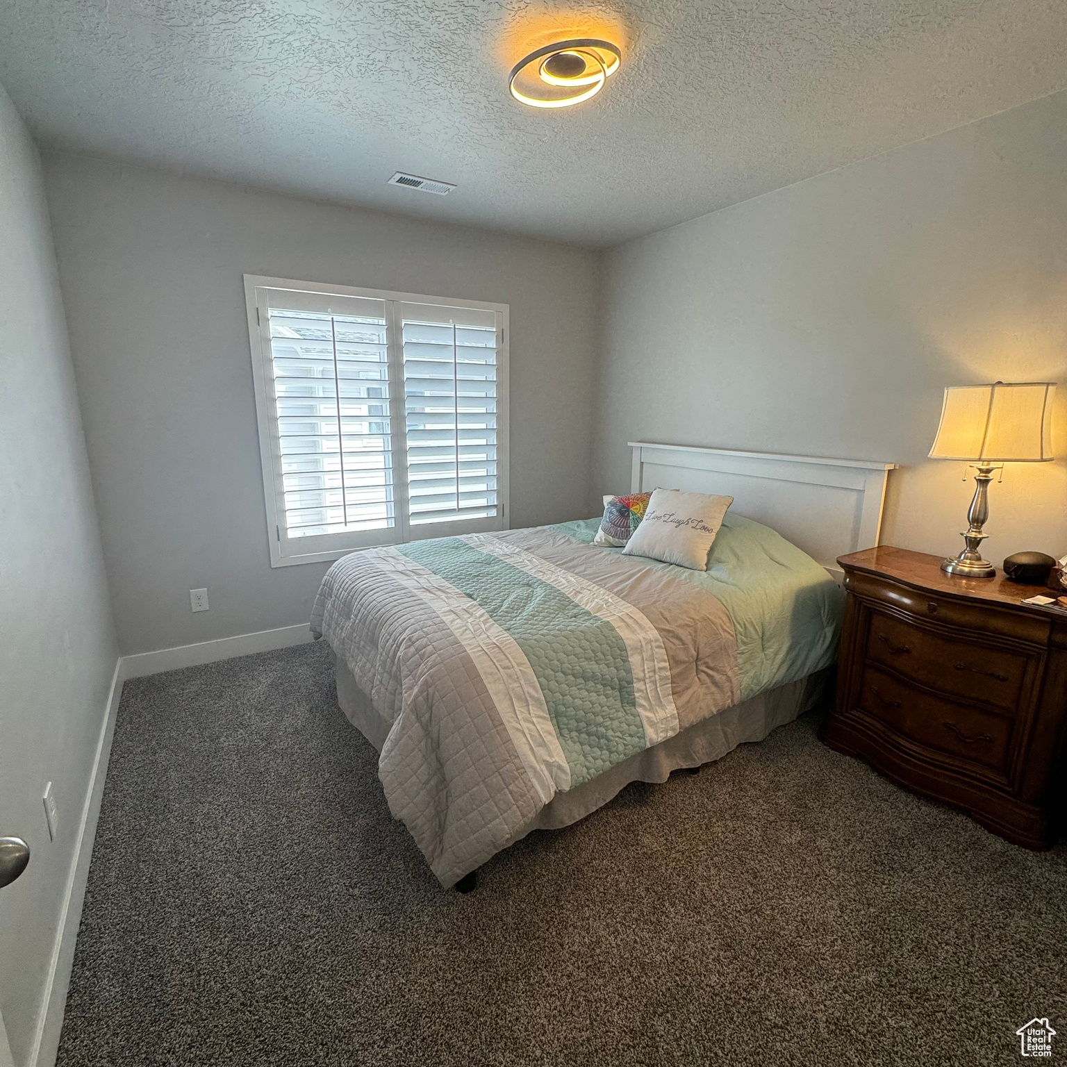 Bedroom with dark colored carpet and a textured ceiling