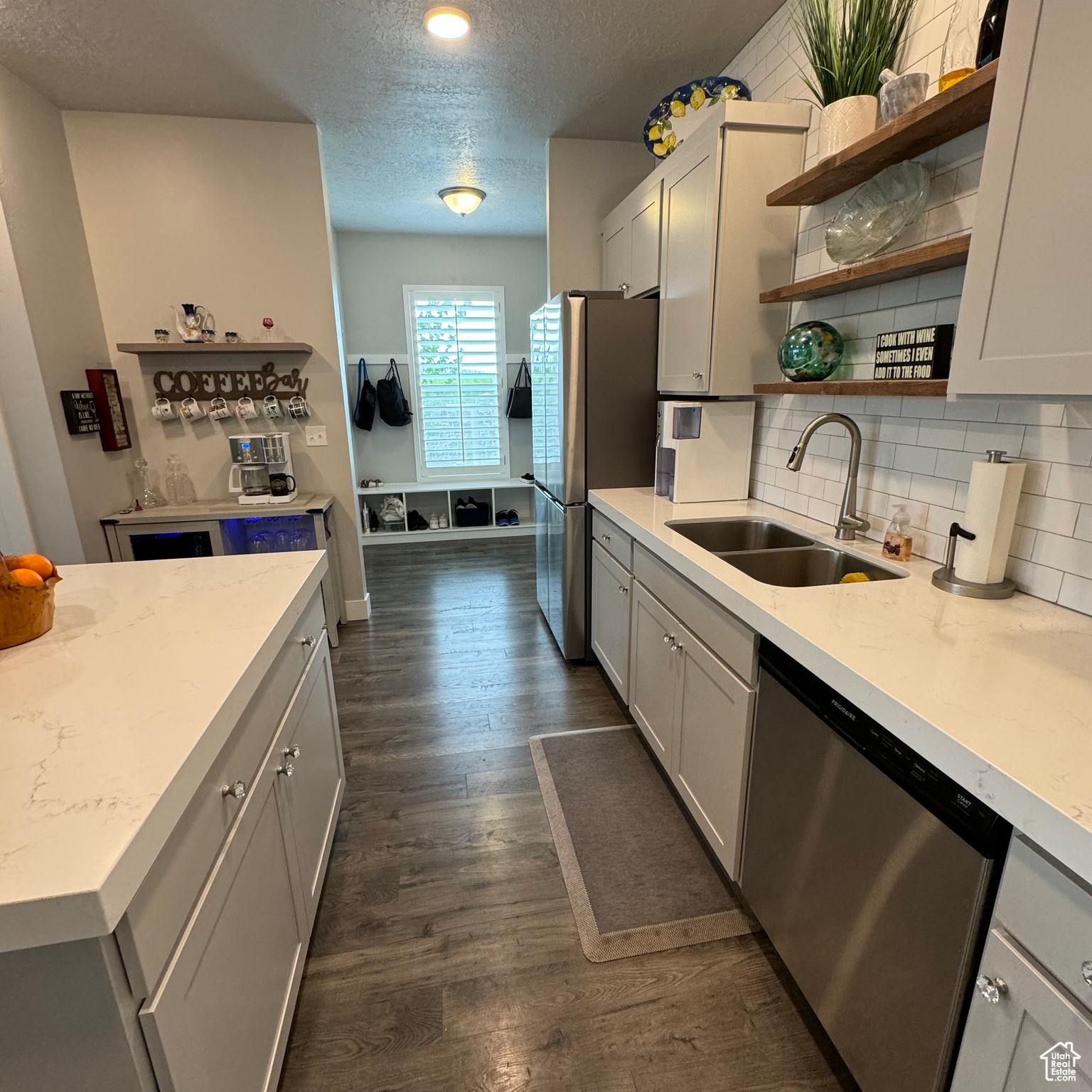 Kitchen with dark hardwood / wood-style floors, stainless steel appliances, sink, tasteful backsplash, and a textured ceiling