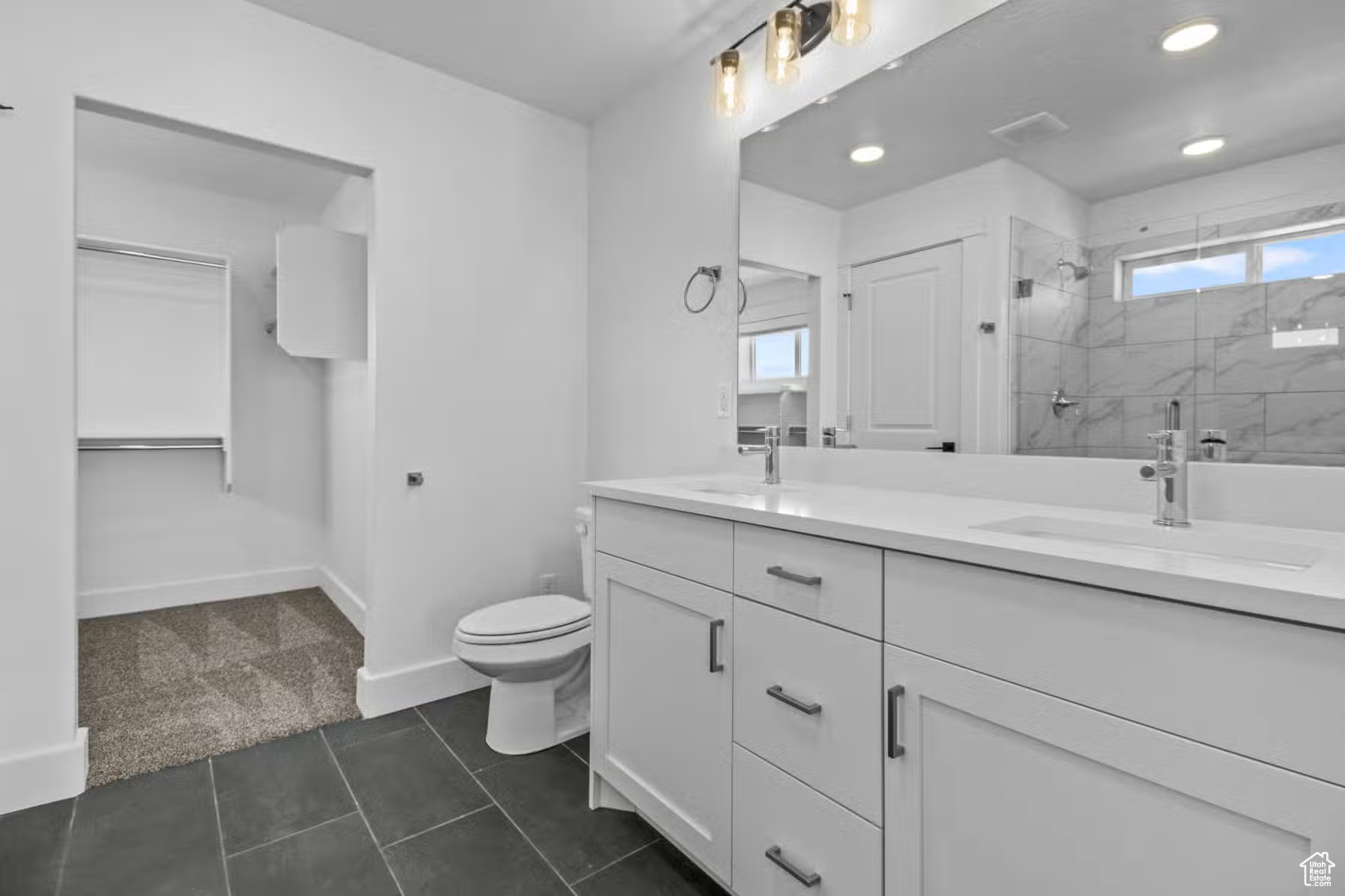 Bathroom with dual sinks, oversized vanity, plenty of natural light, toilet, and tile floors