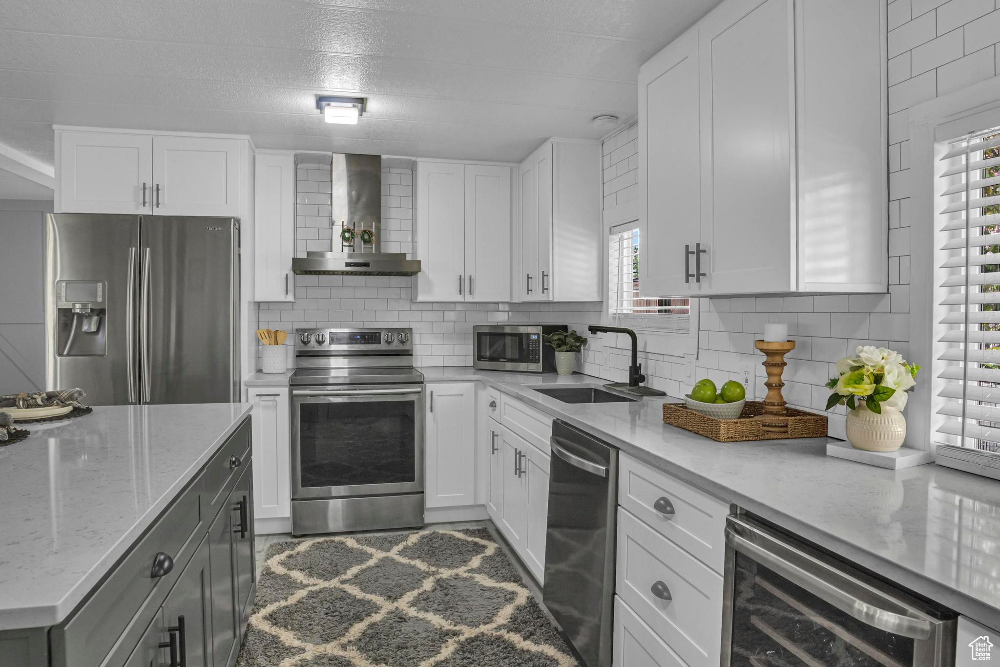 Kitchen with a healthy amount of sunlight, appliances with stainless steel finishes, sink, and beverage cooler