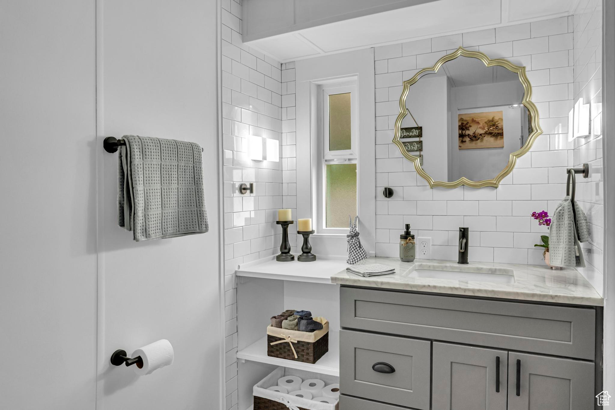 Bathroom with backsplash, vanity, and tile walls