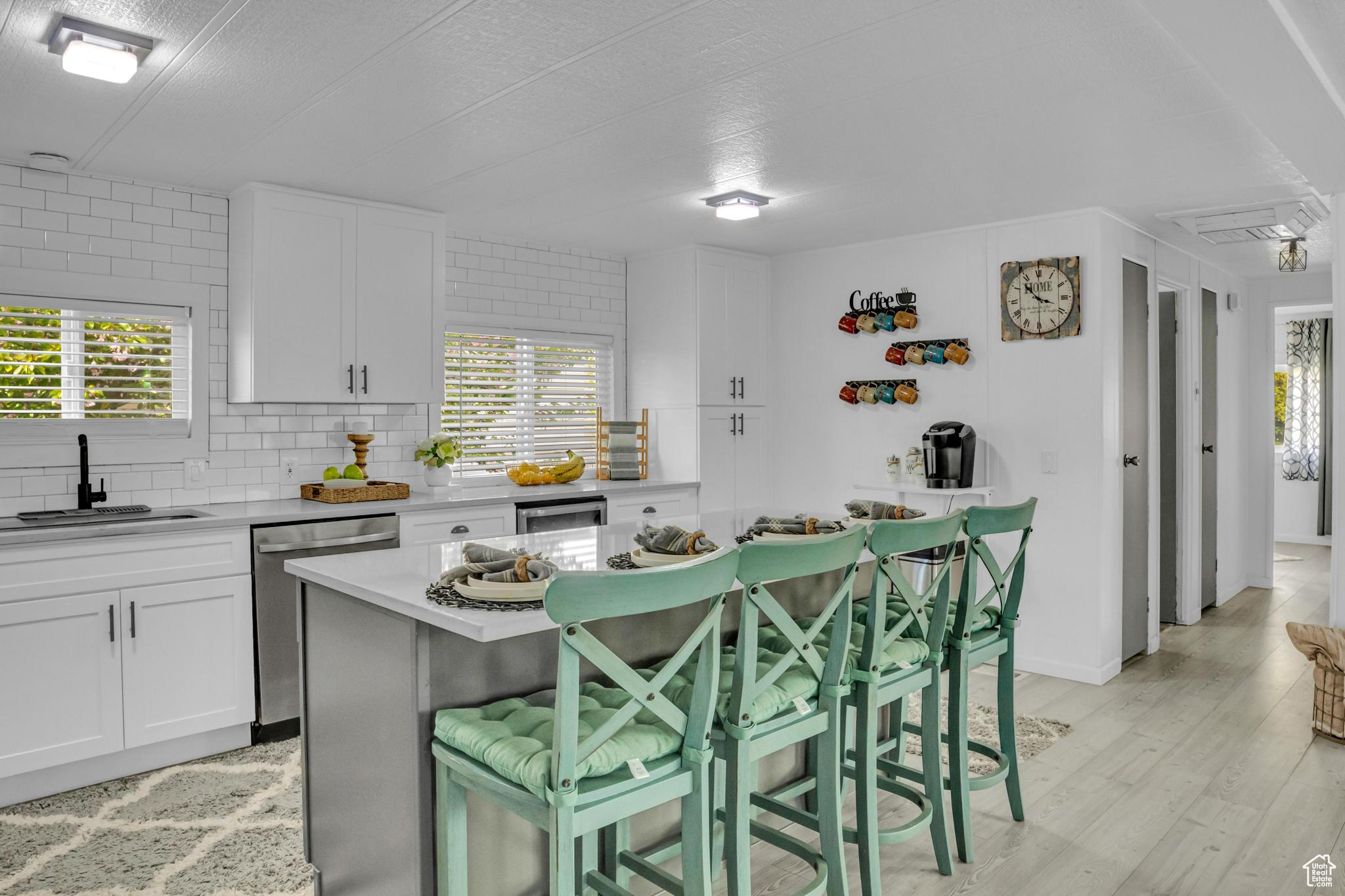 Kitchen with a wealth of natural light, dishwasher, sink, and light wood-type flooring